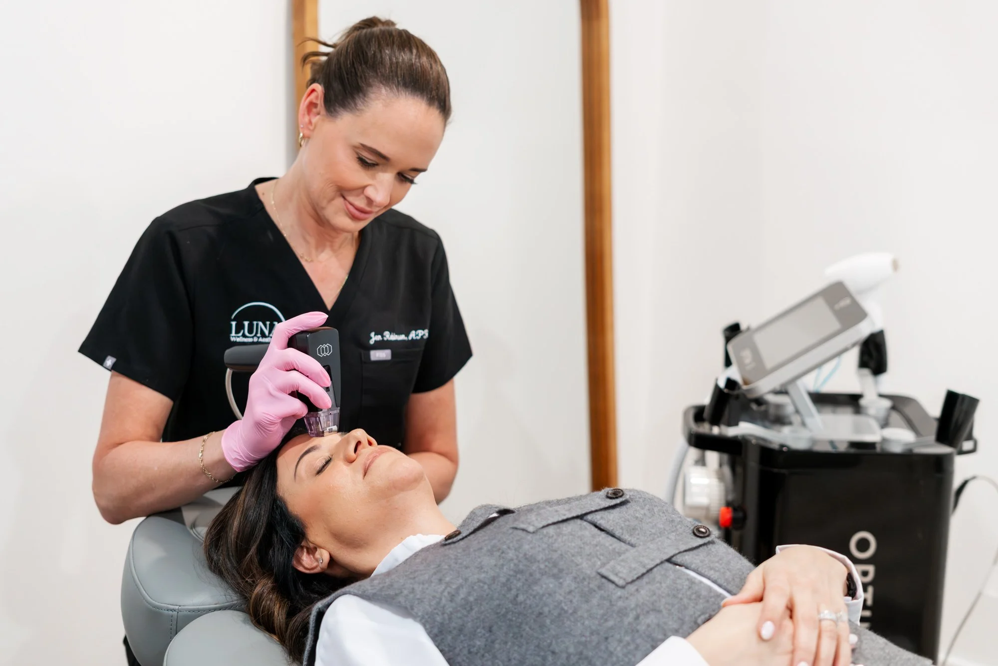 A woman receiving a cosmetic facial treatment with a device from a healthcare professional in a clinic