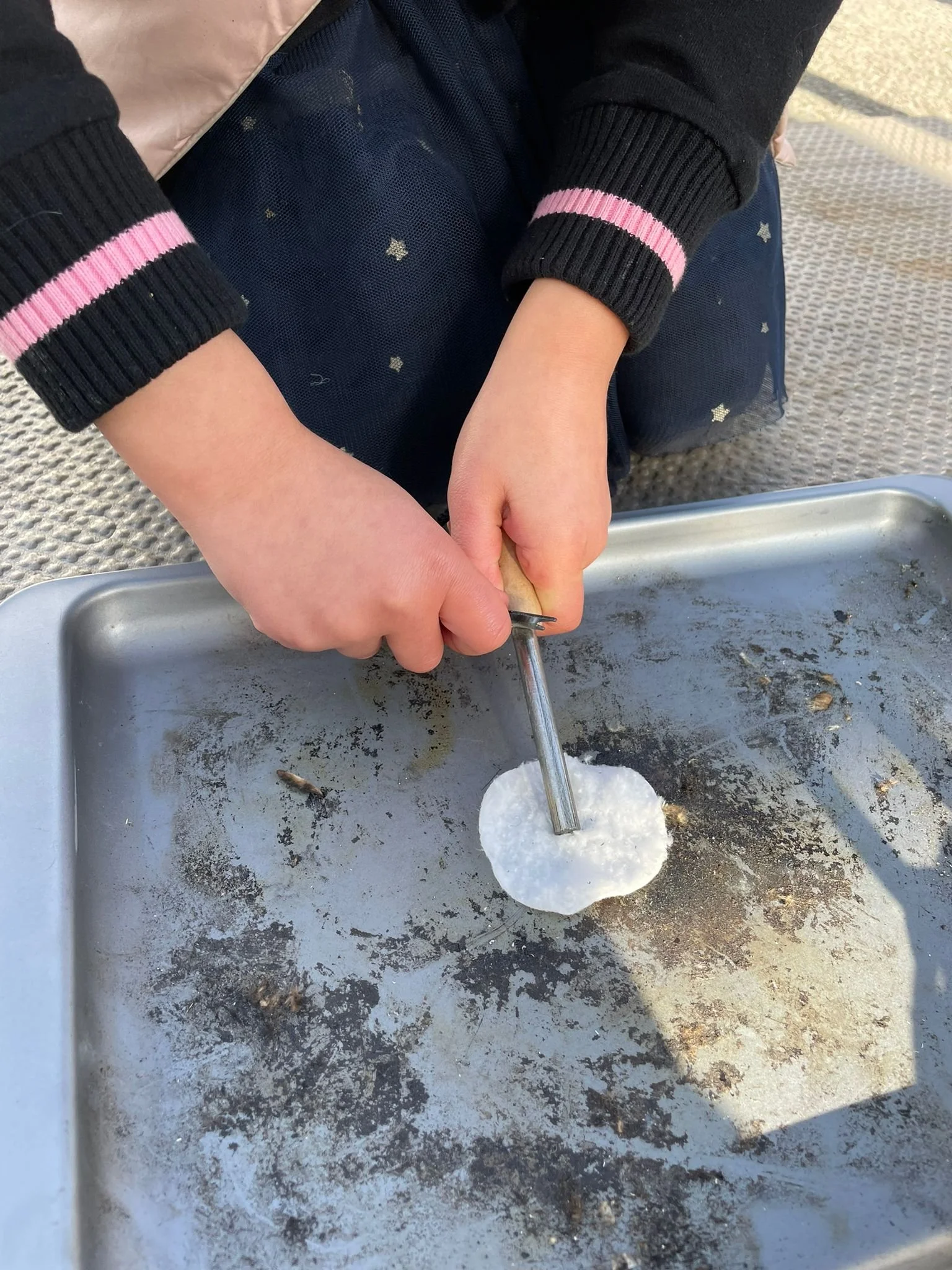 A young child making a homemade pizza in a baking tray using a 3D printed pizza cutter.