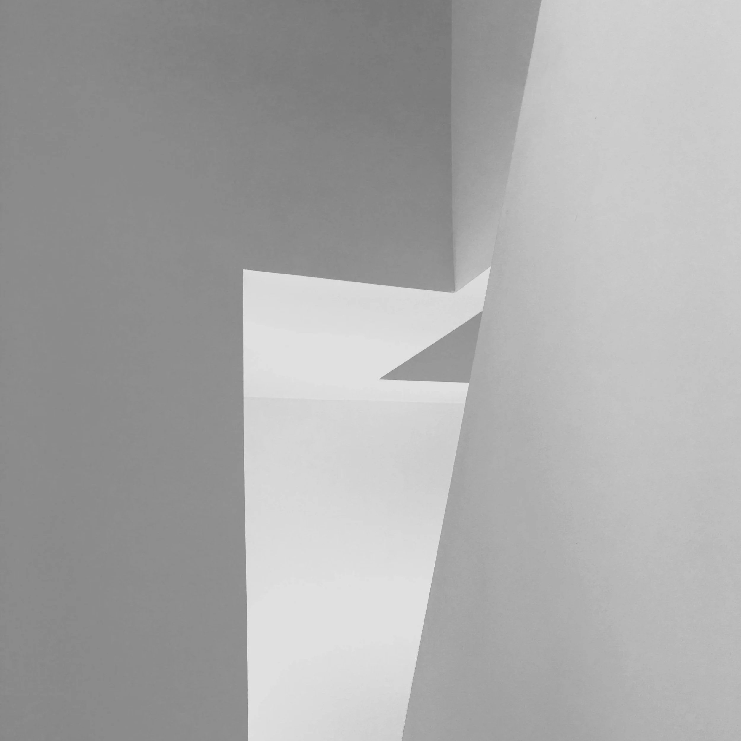 Abstract composition of angular white and gray geometric shapes creating a dynamic, modern visual effect.