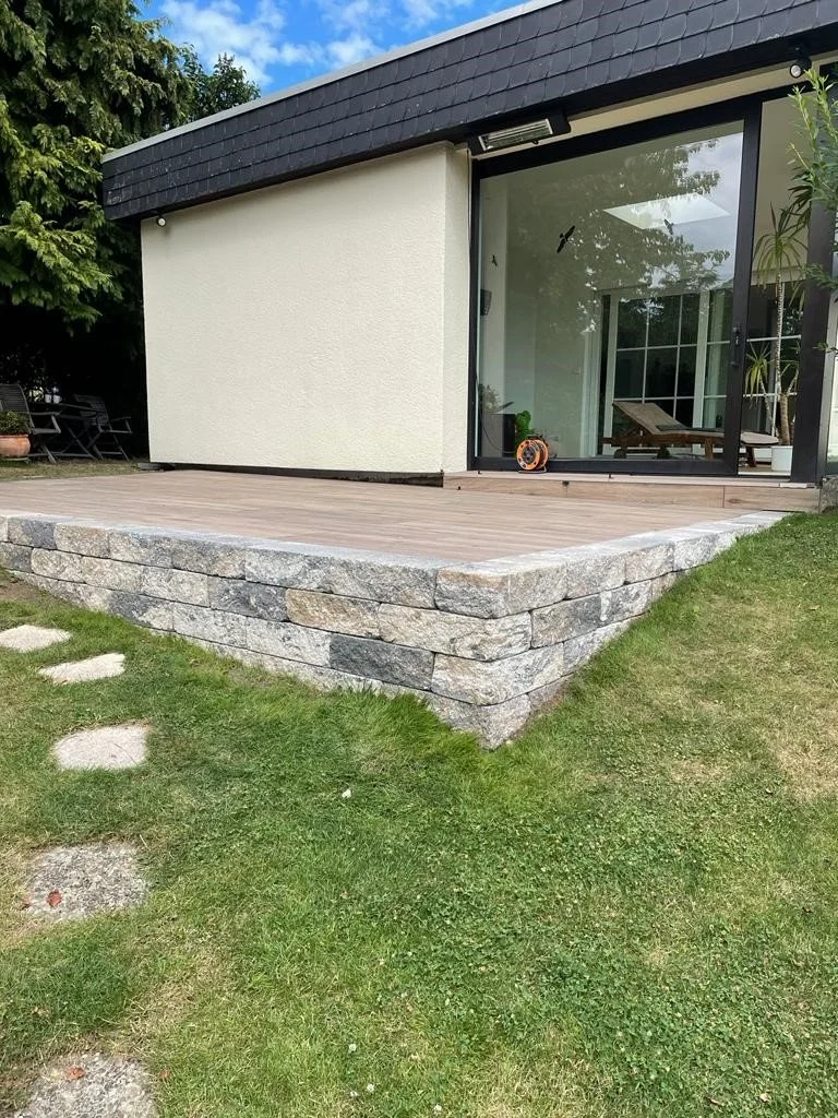 Erhöhte Gartenterrasse mit Podest und robuster Naturstein-Unterkonstruktion im Hanggarten