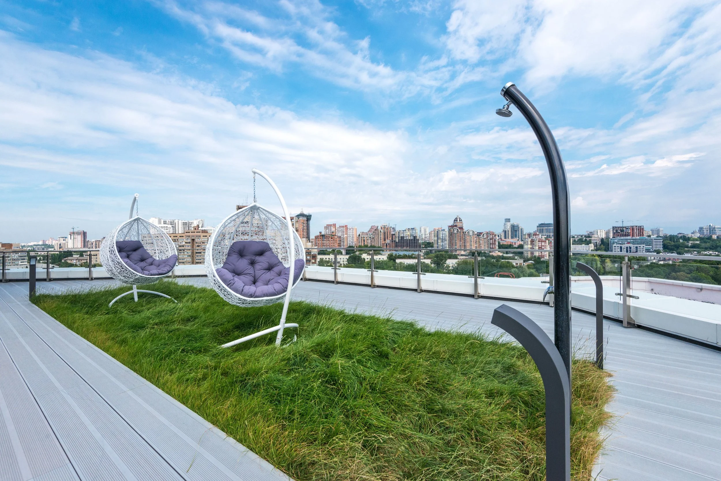 Moderne intensive Dachbegrünung mit Rasenfläche, Hängesesseln und Aussicht über die Stadt