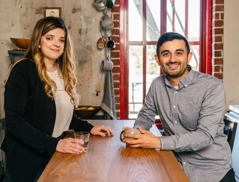 Two employees stand at a table in an office kitchen.
