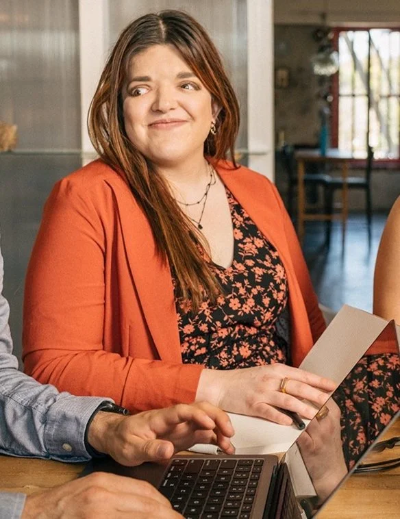A smiling employee is seen standing in an office.