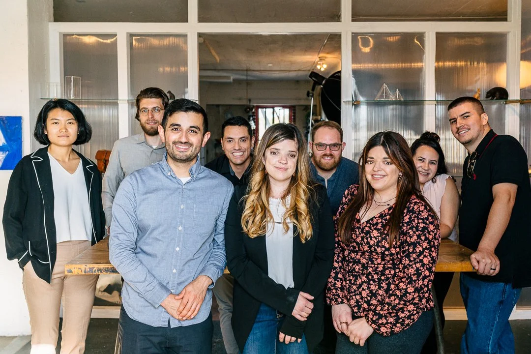 Nine men and women, shown to be True Sparrow employees, stand around a conference table in their office.