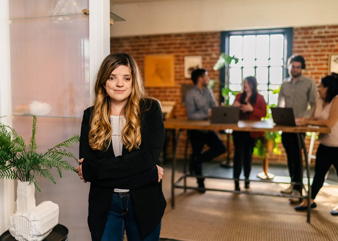 Professional headshot of Alixandria Henley standing in an office with her arms folded in front of her.