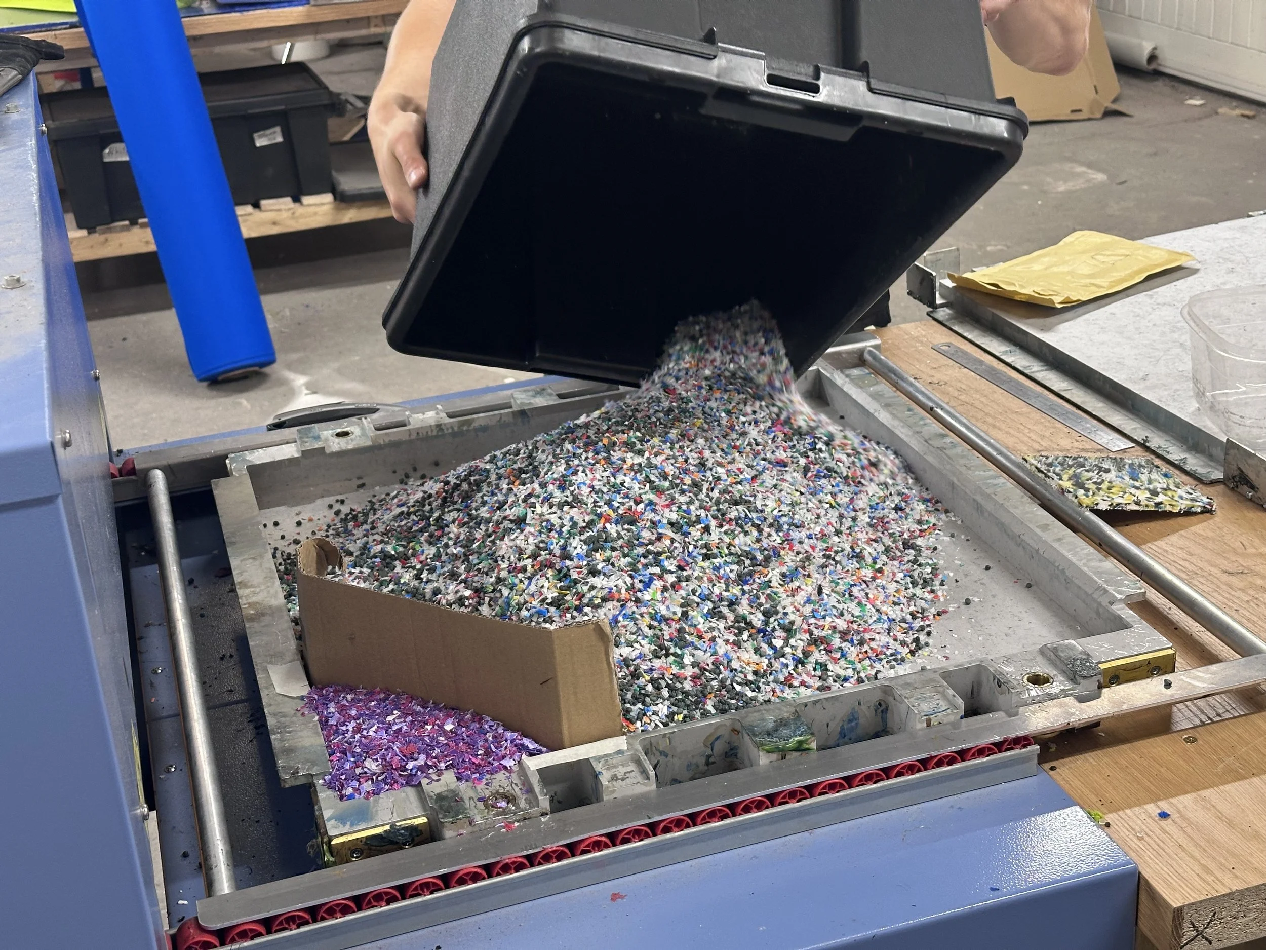 Granulated bottle tops being poured into the mould cassette with a purple corner