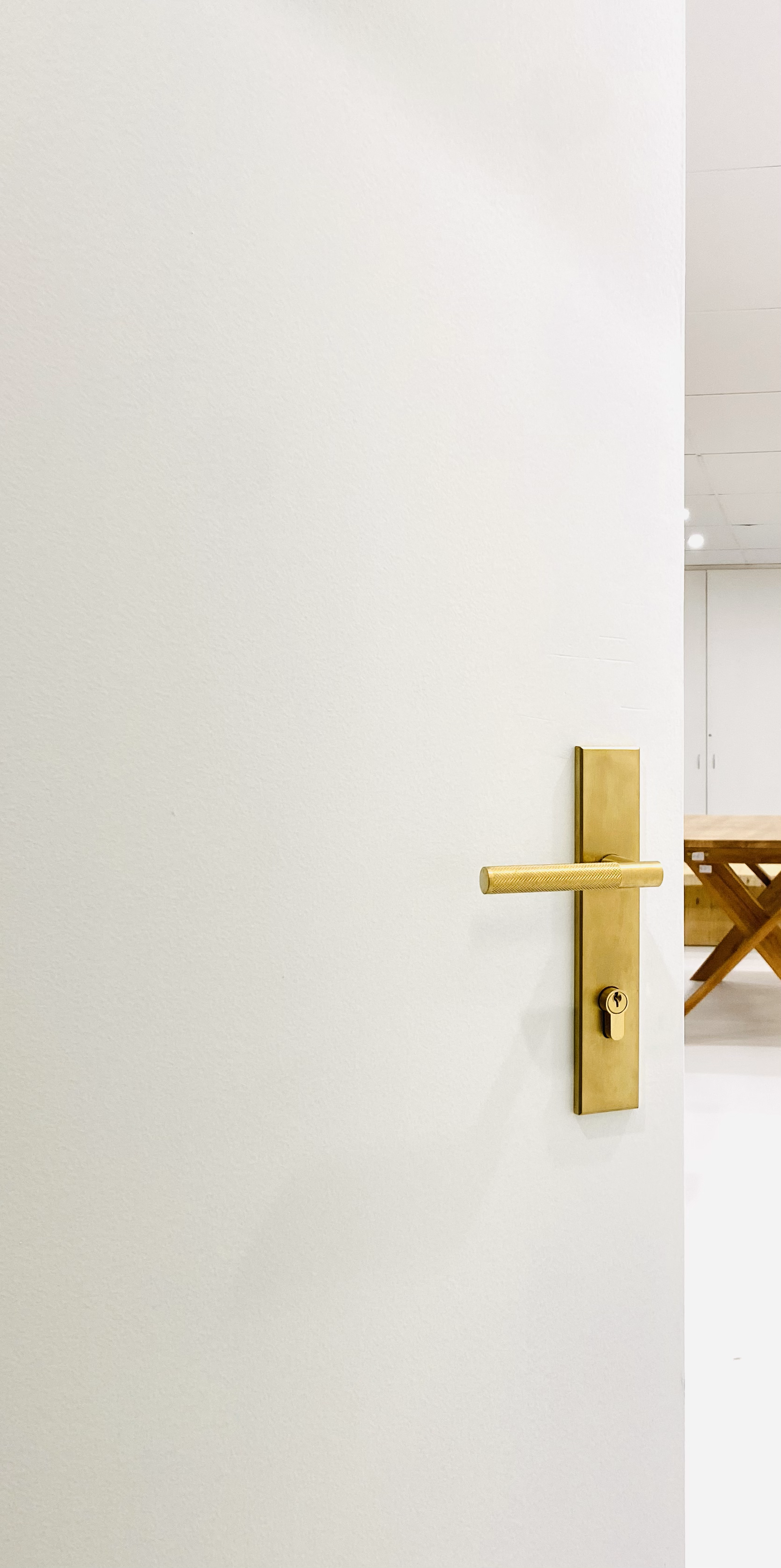 A door with a gold-colored handle and lock in a white wall.