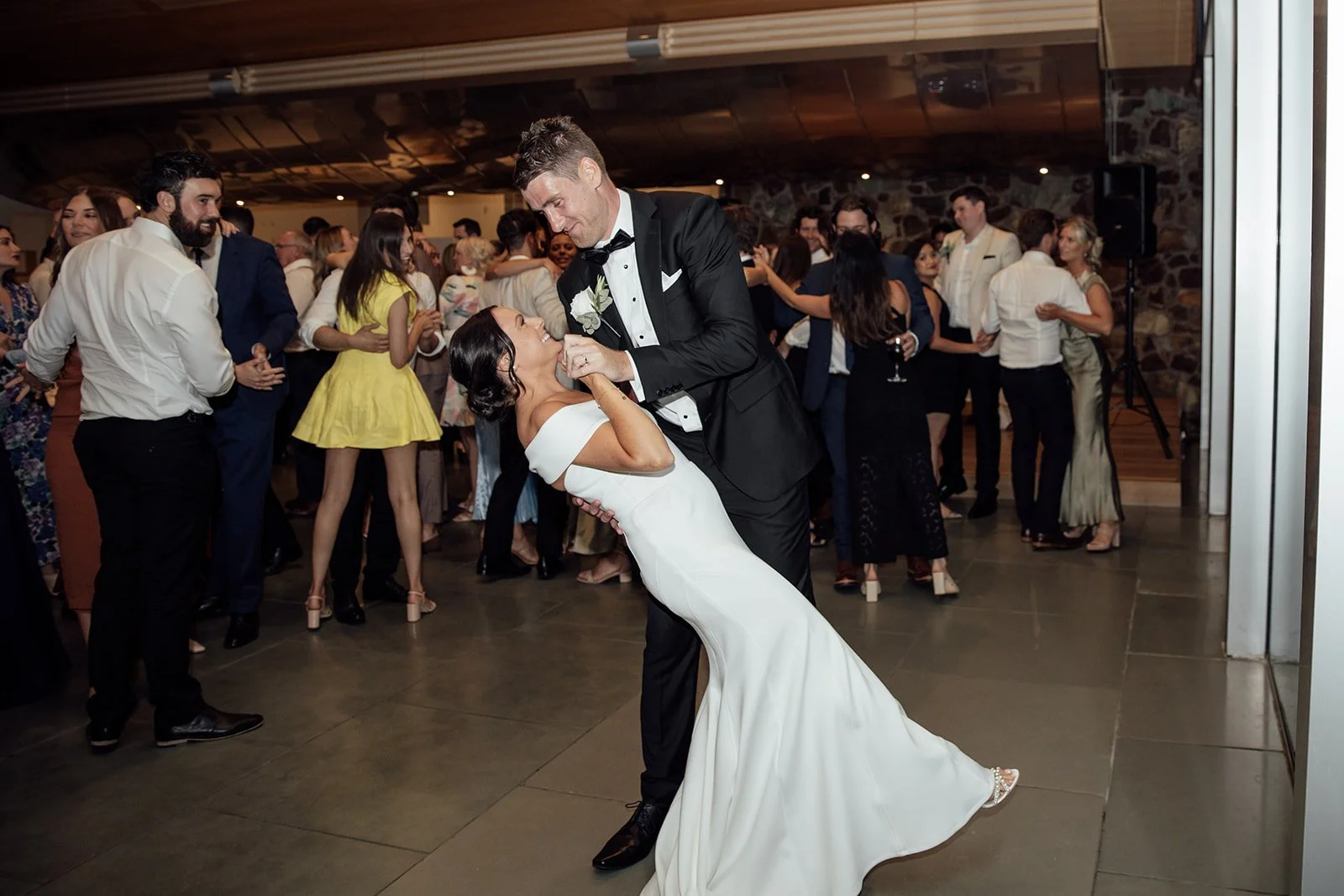 A groom dips his bride back as they dance hand-in-hand on the dancefloor, smiling at Yering Station in Yarra Valley.