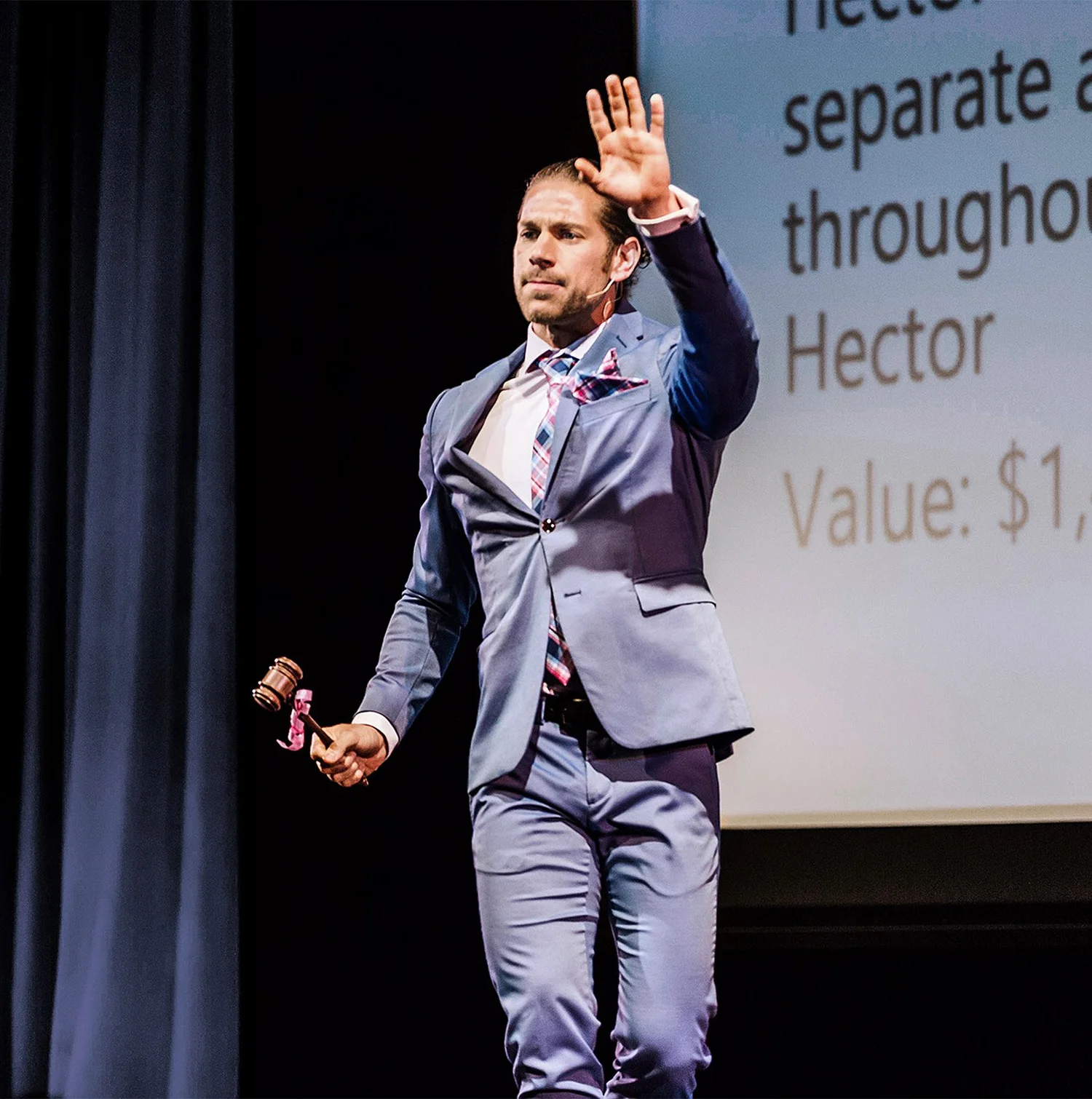 Benjamin onstage with his hand raised during a benefit auction