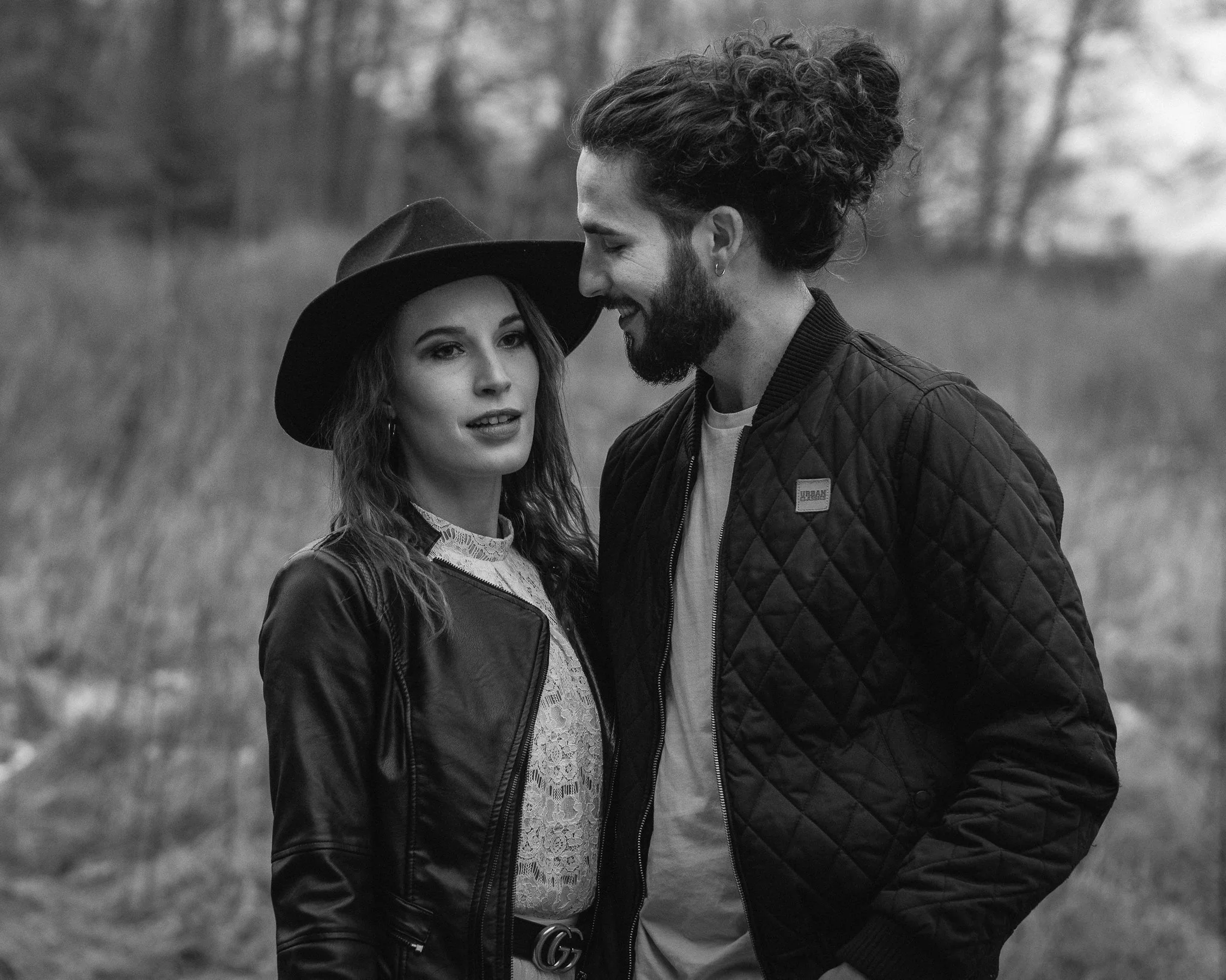 Ein Mann und eine Frau stehen nahe beieinander im Freien, lachen und schauen sich an. Es ist schwarz-weiß.