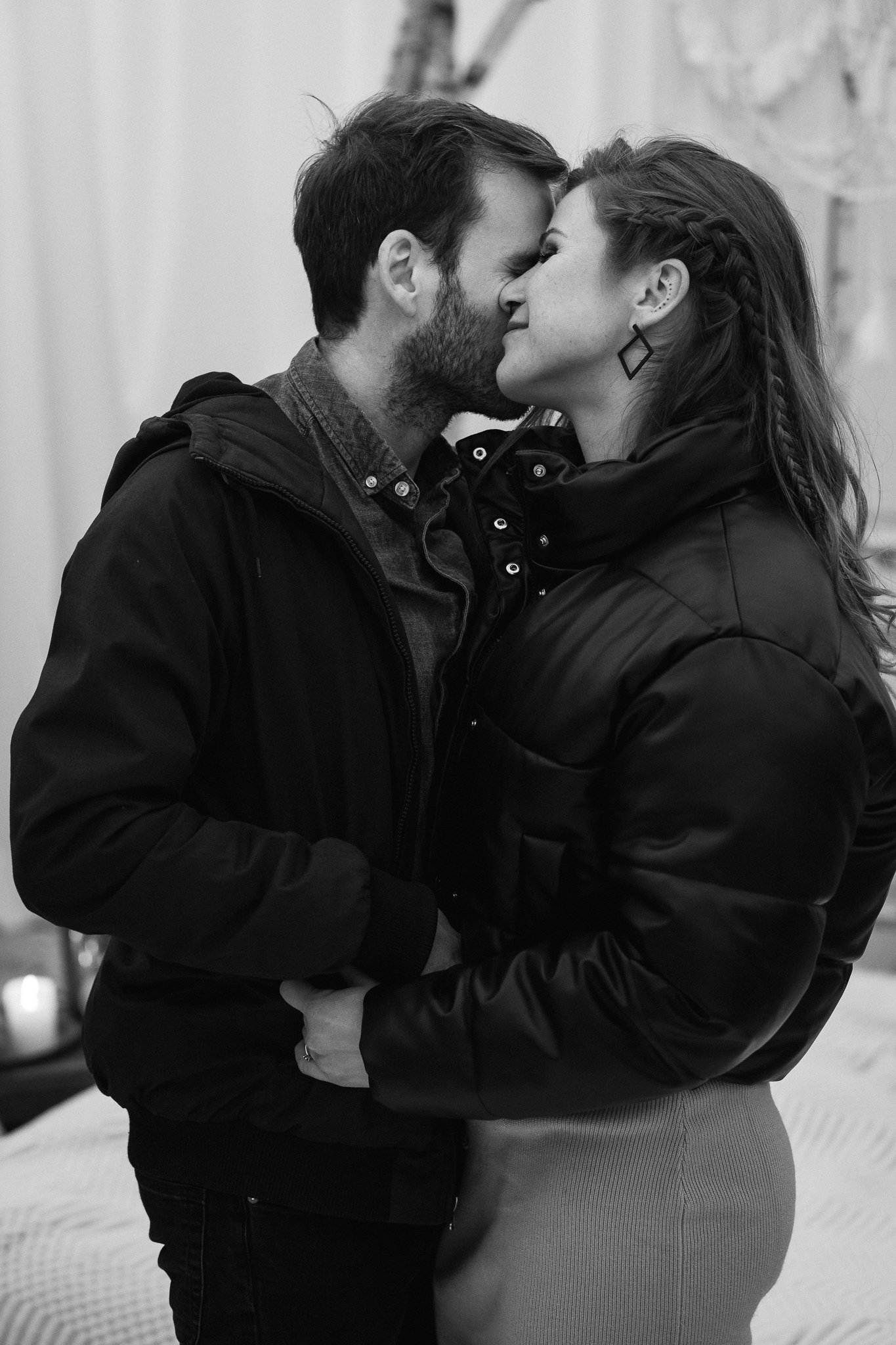 Ein schwarz-weiß Foto eines Paares, das sich liebevoll küsst, mit den Stirnen aneinander, in einer intimen Haltung, beide tragen dicke Jacken.