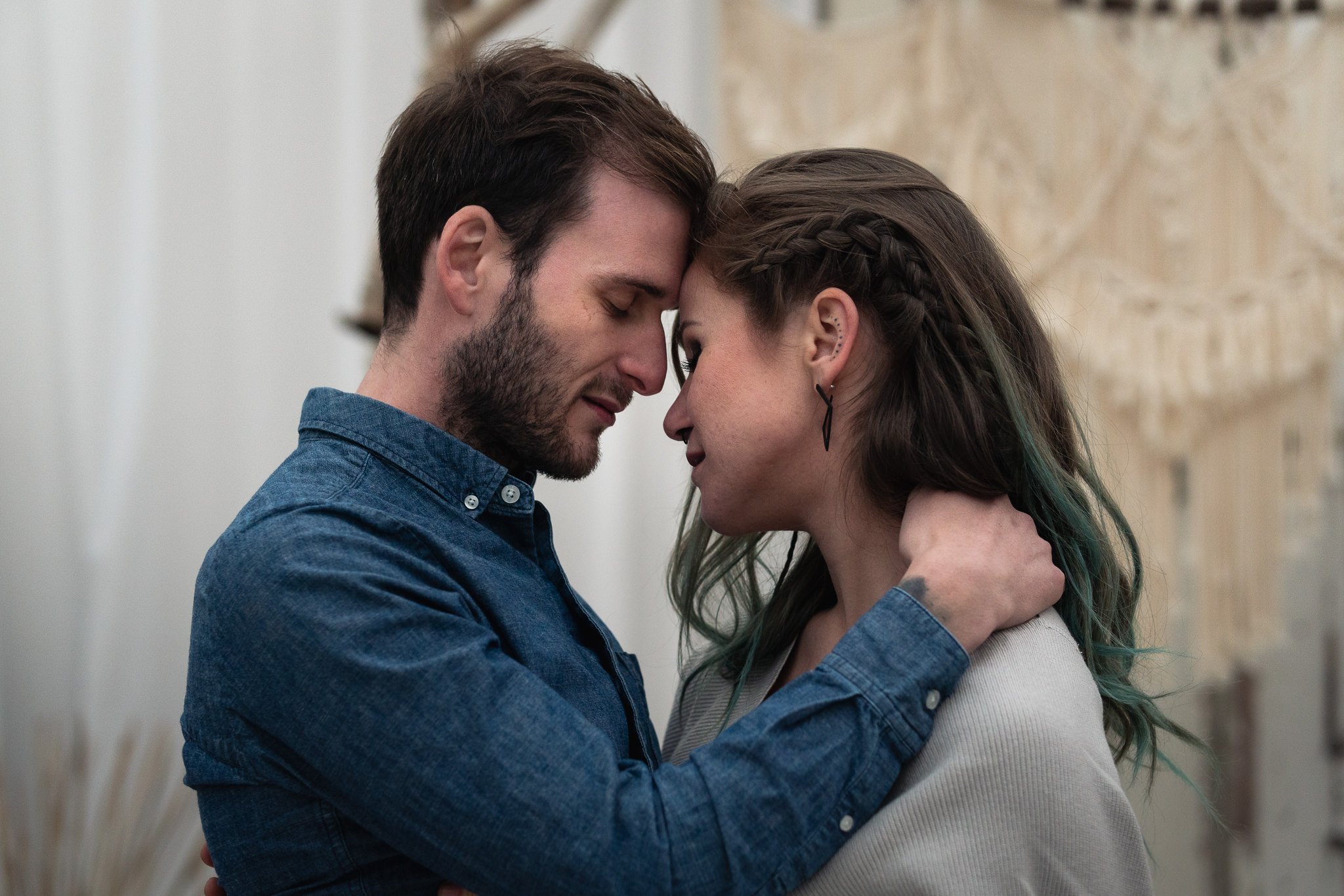 Ein Mann und eine Frau stehen sich mit geschlossenen Augen und ihren Stirnen aneinander, in einer intimen Geste, die Zuneigung zeigt.