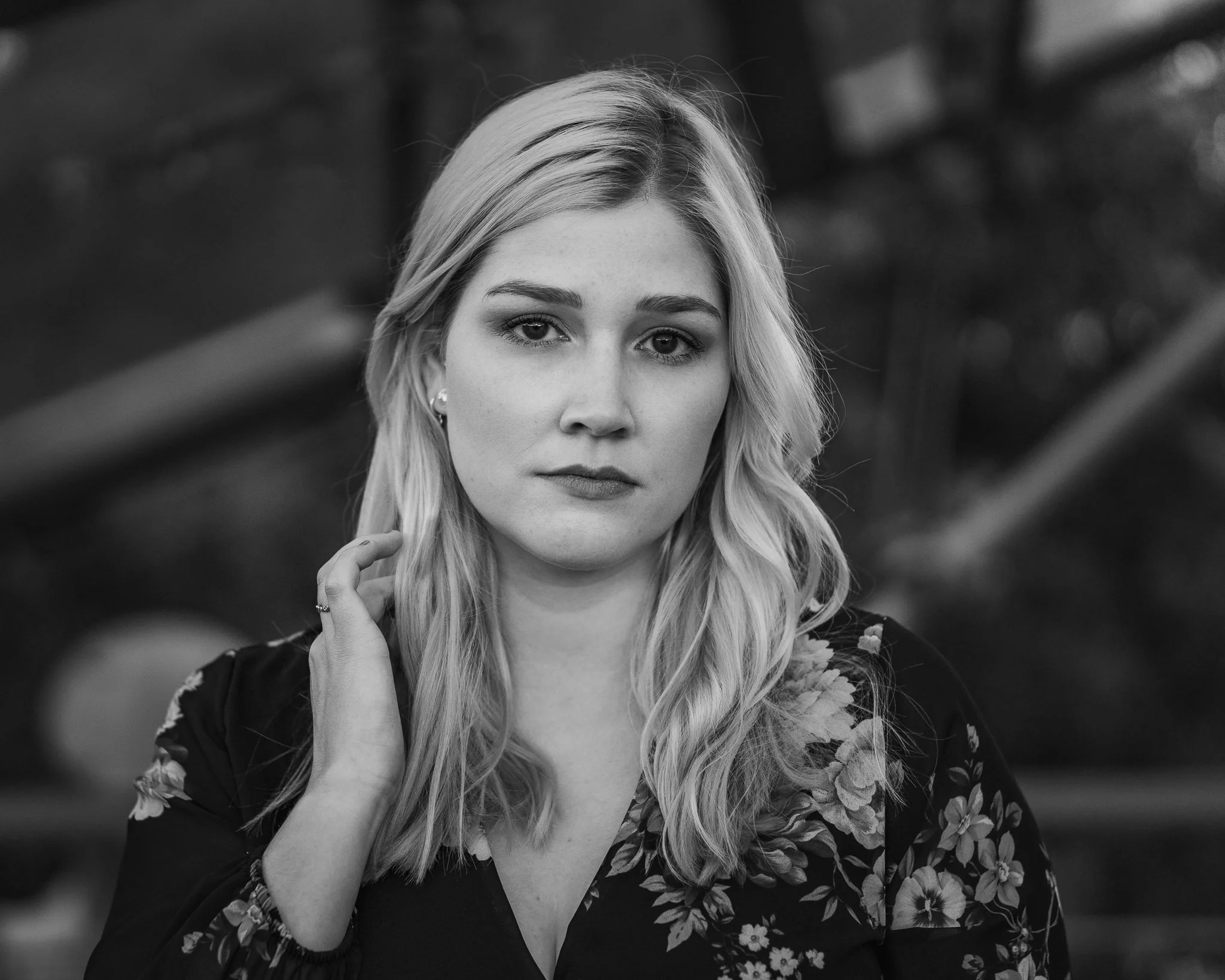 Schwarz-Weiß-Foto eines jungen Mädchens mit langen, gewellten Haaren, das einen nachdenklichen Ausdruck zeigt, im Freien mit unscharfem Hintergrund.