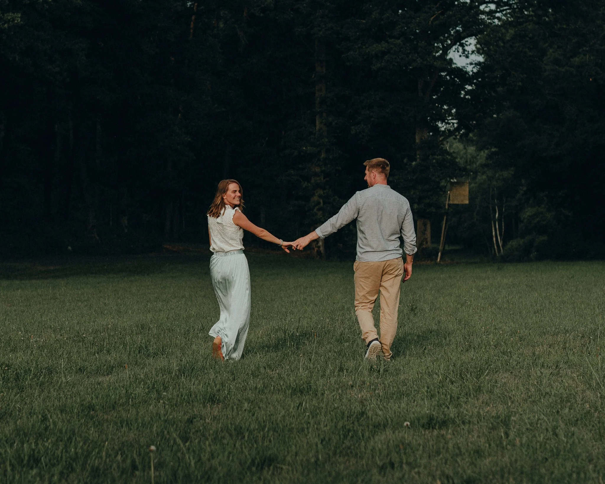 Ein Paar tanzt draußen auf einer Wiese bei Sonnenuntergang.