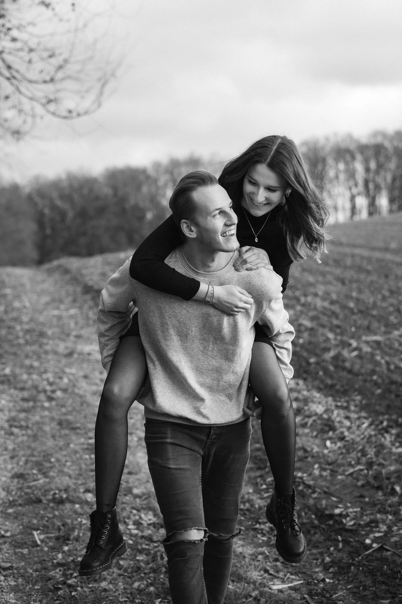 Ein Lächelndes Paar, das im Freien spazieren geht, wobei die Frau auf den Schultern des Mannes sitzt.