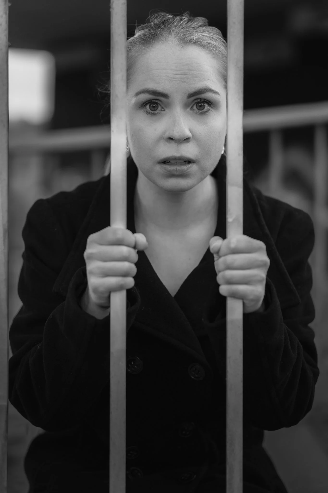 Schwangere Frau schaut durch Gitter und wirkt nachdenklich oder besorgt.