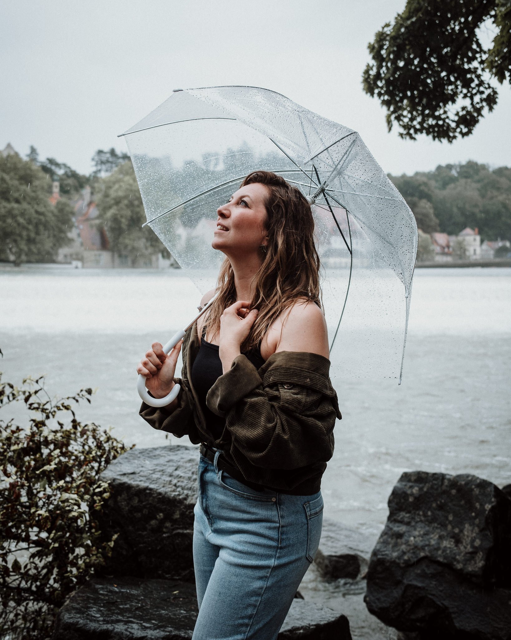 Frau mit Regenschirm am Wasser bei Regenwetter