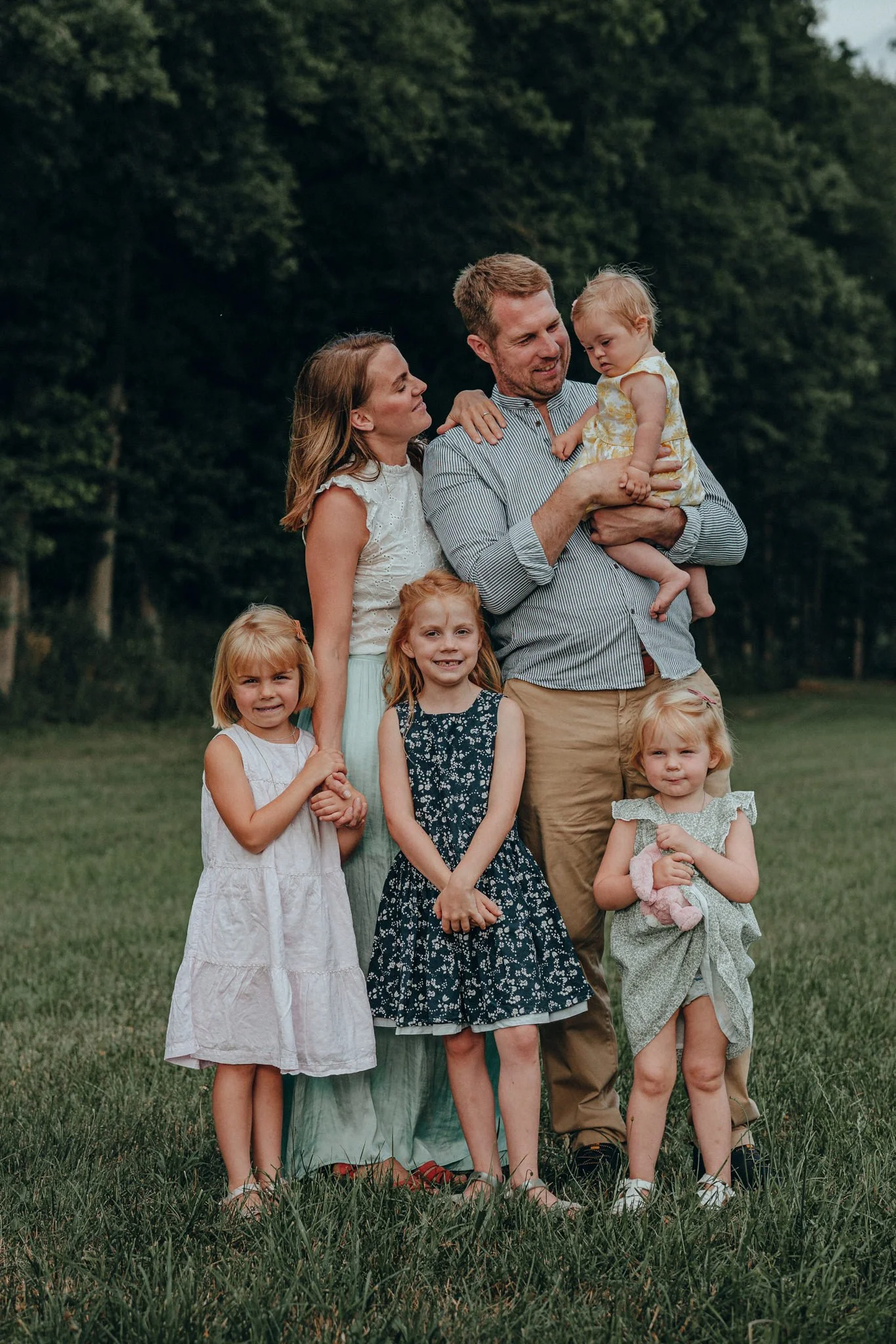 Familie mit drei erwachsenen Frauen und drei Mädchen im Freien, umgeben von Bäumen, beim Fotoshooting im Grünen.