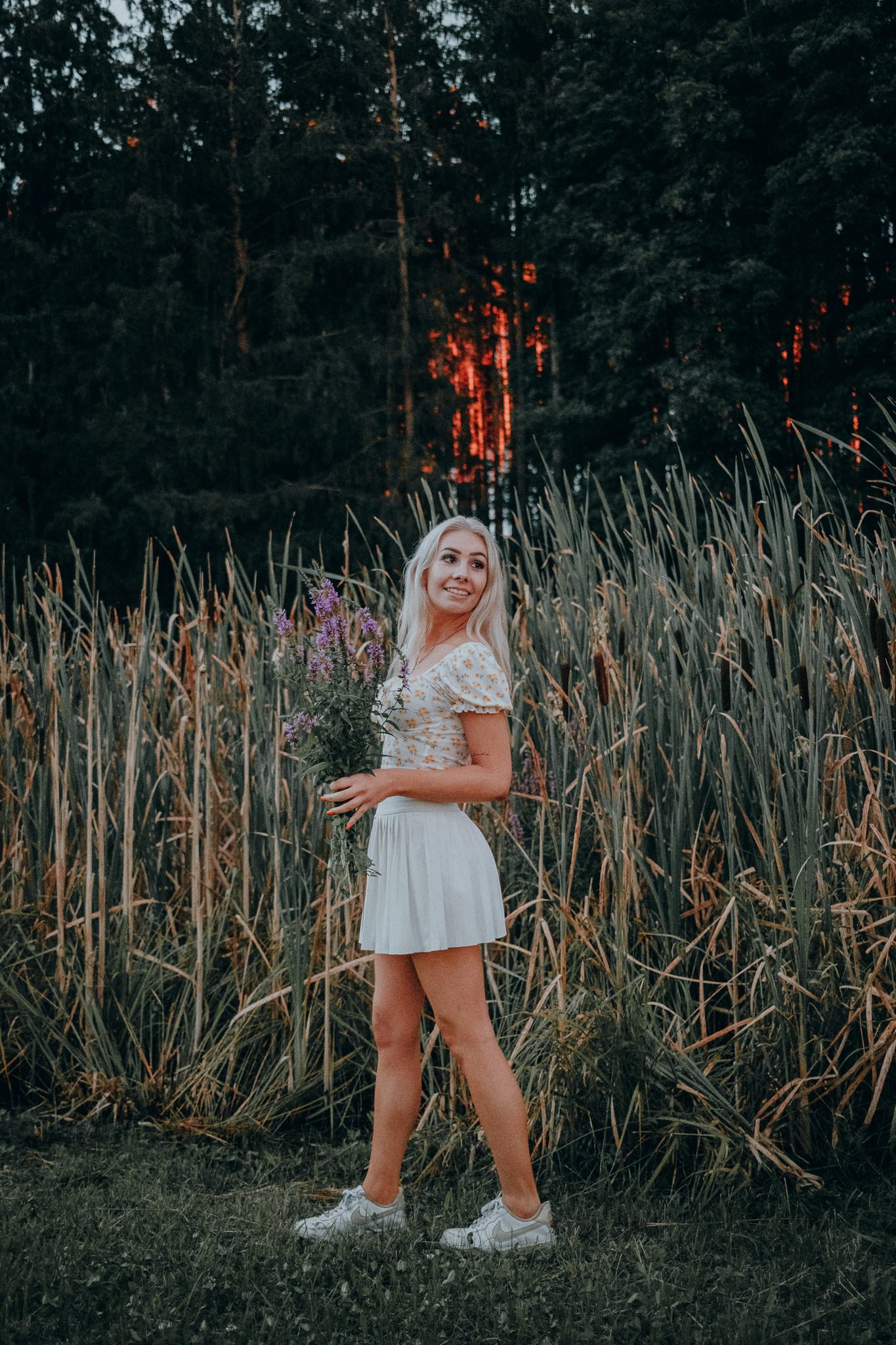 Junge Frau mit Blumenstrauß im Feld bei Sonnenuntergang