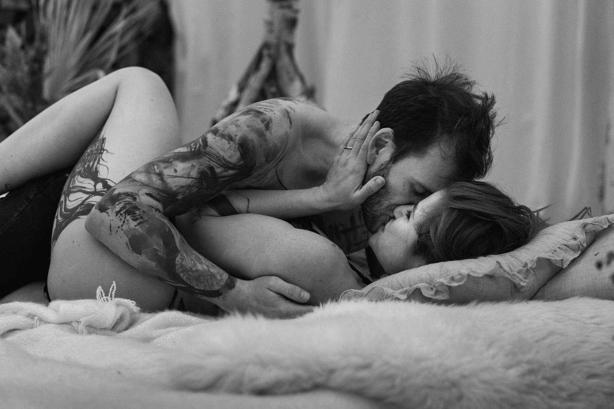 Ein Mann und eine Frau liegen auf einem Bett und küssen sich leidenschaftlich.