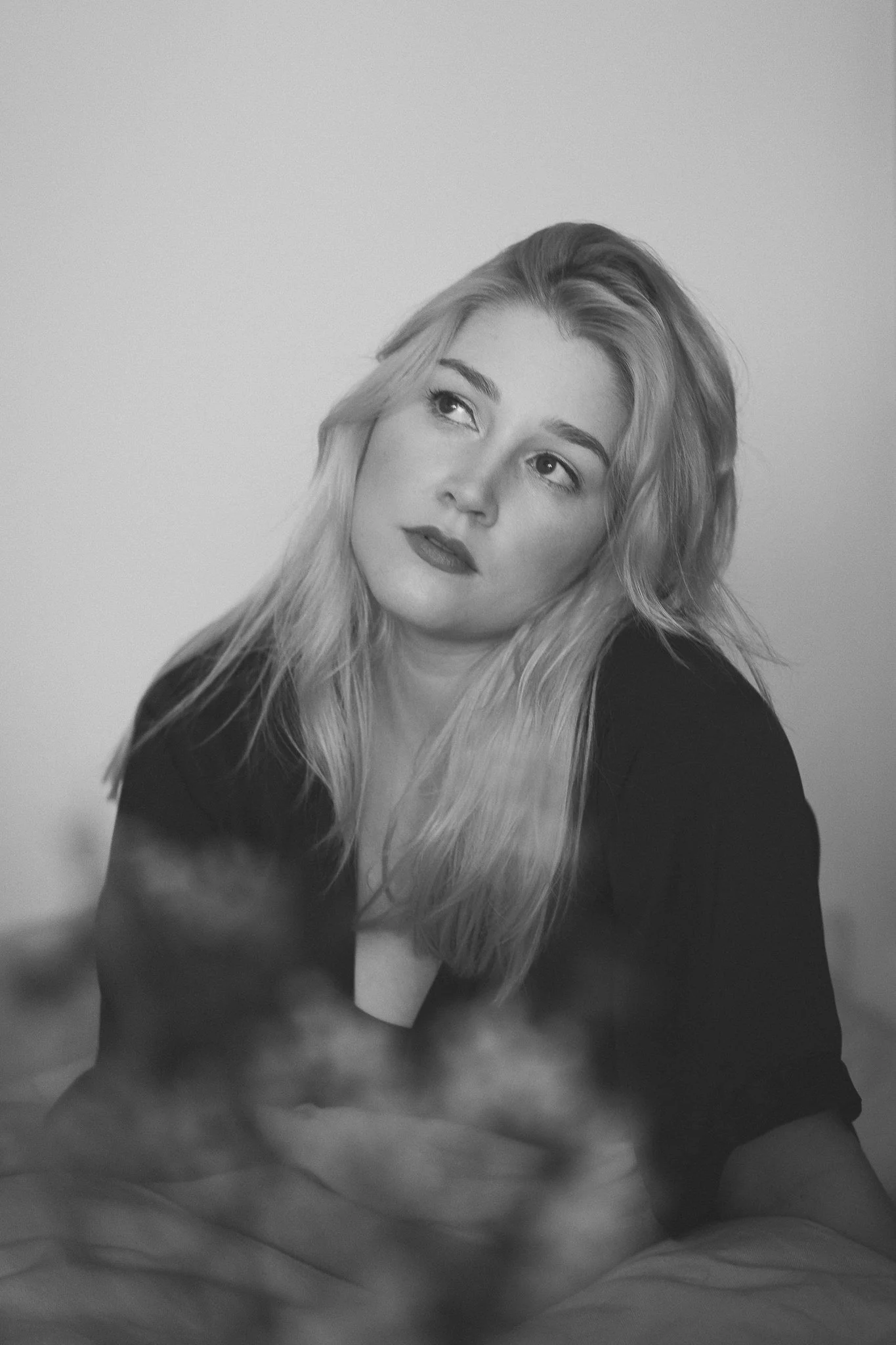 Schwarz-weiß-Foto einer jungen Frau mit langem, wavy Haar, die nachdenklich blickt.