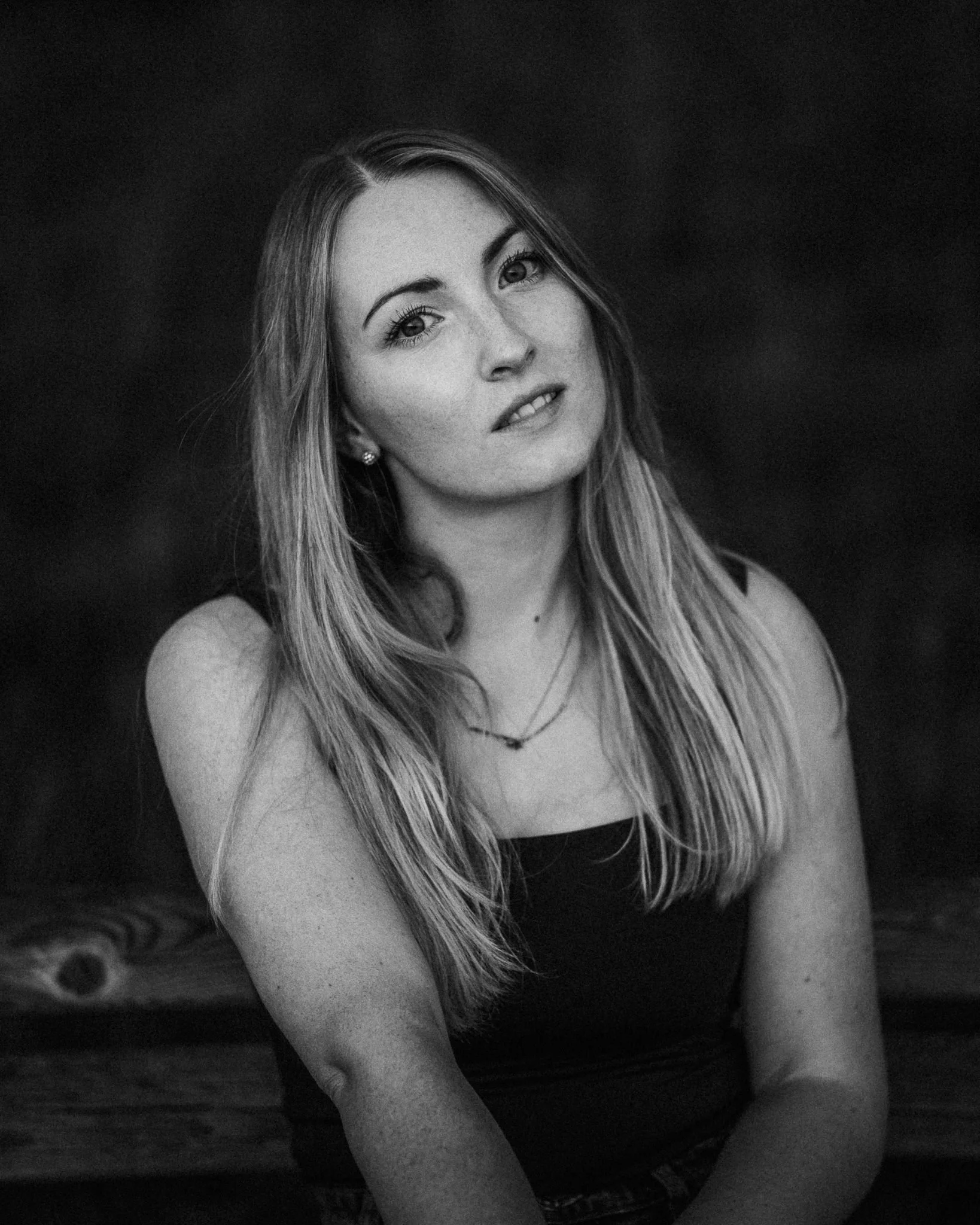 Schwarz-weiße Aufnahme einer jungen Frau mit langen, glatten Haaren, die leicht lächelt und in die Kamera schaut.