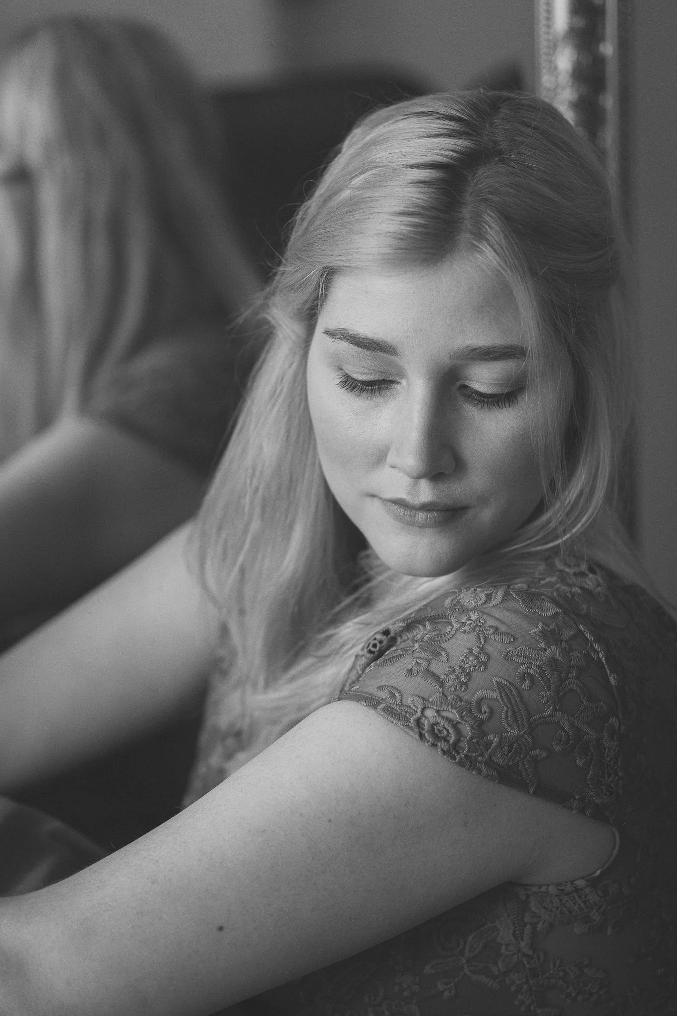 Schwarz-Weiß-Fotografie eines jungen Mädchens mit geschlossener Augenpartie, das seitlich schaut und ein elegantes Kleid trägt.