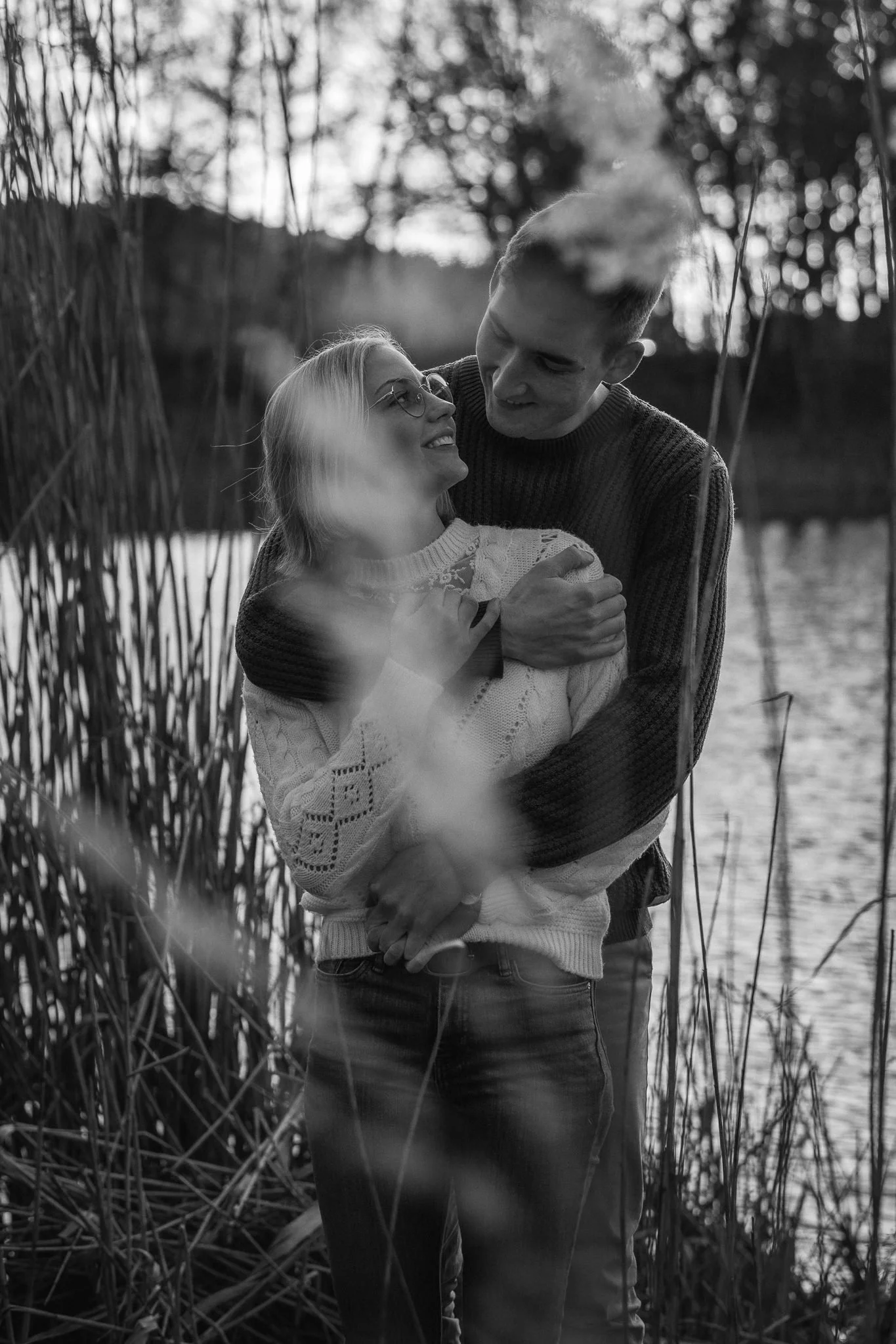 Ein Paar umarmt sich an einem Flussufer im Freien bei Sonnenuntergang.