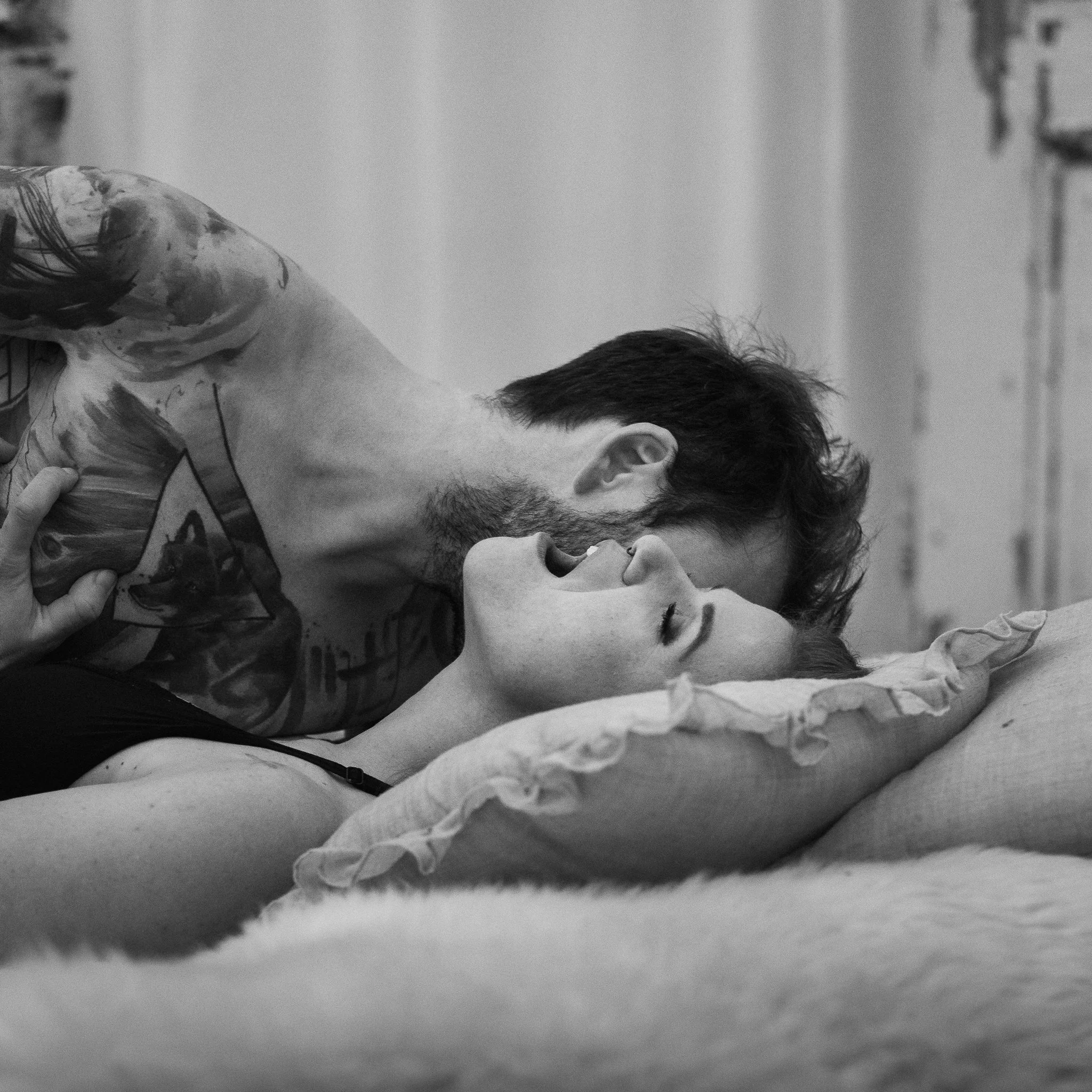 Ein Mann und eine Frau liegen sich eng gegenüber auf einem Bett, im Moment einer intimen Umarmung oder Berührung.