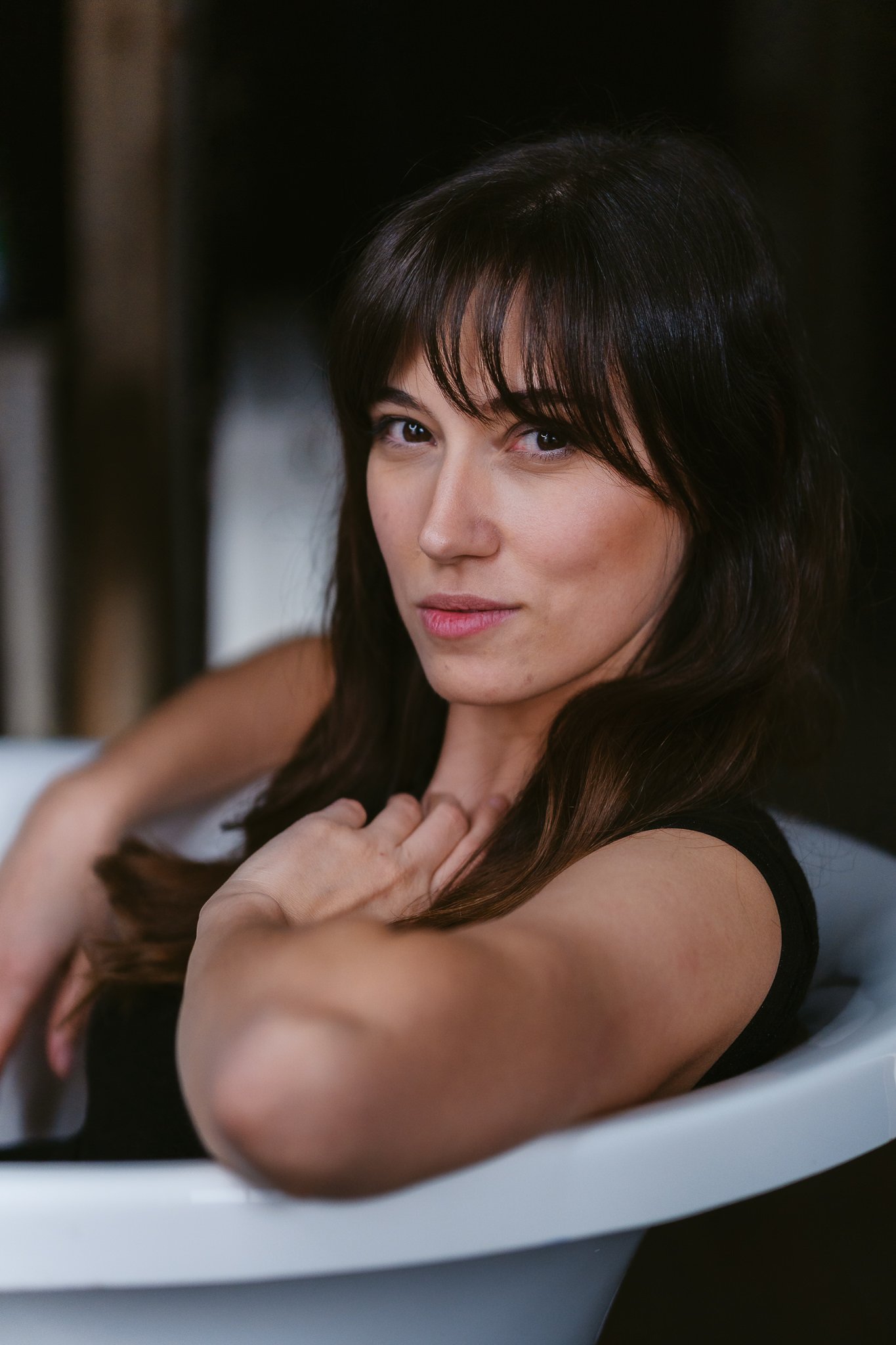 Junge Frau mit dunklem Haar, liegt im Badewannen, Blick in die Kamera, entspannte Pose, innige Atmosphäre