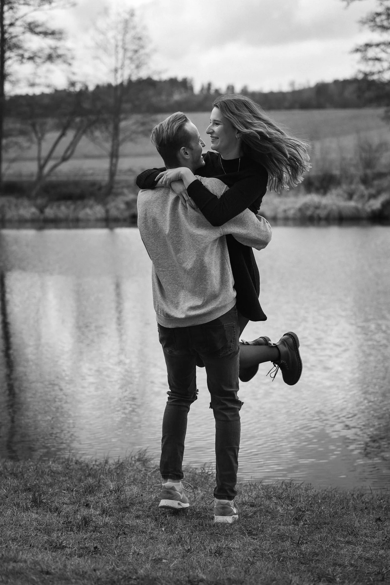 Ein Paar umarmt sich am Ufer eines Flusses in einer natürlichen, ruhigen Umgebung.