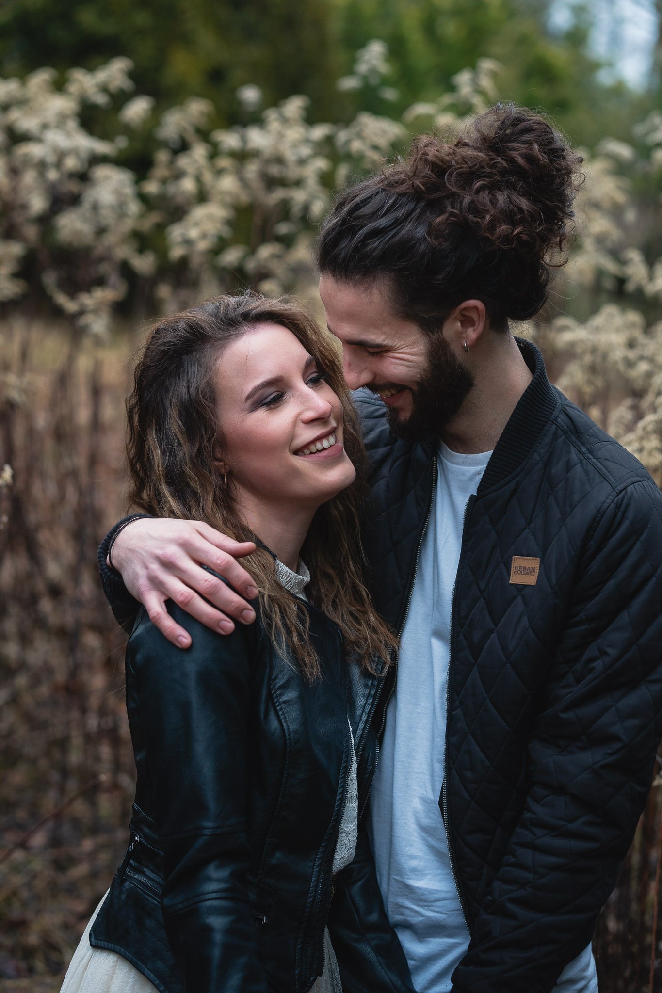 Ein lachendes Paar in einem Wald, umarmend.