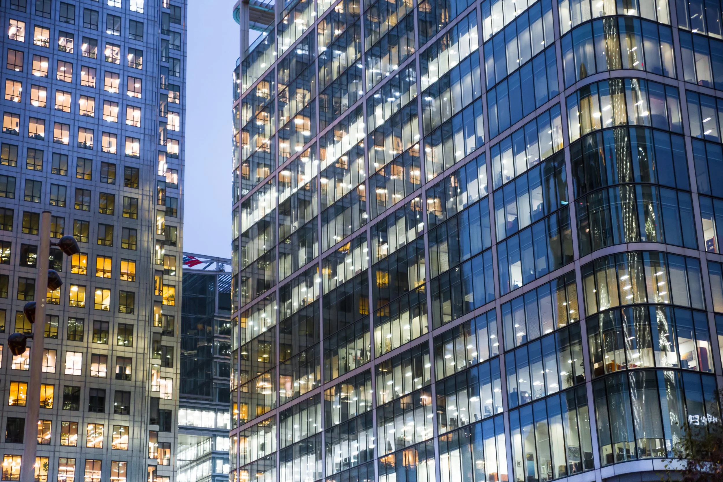 Night view of illuminated office buildings with glass facades in a city.