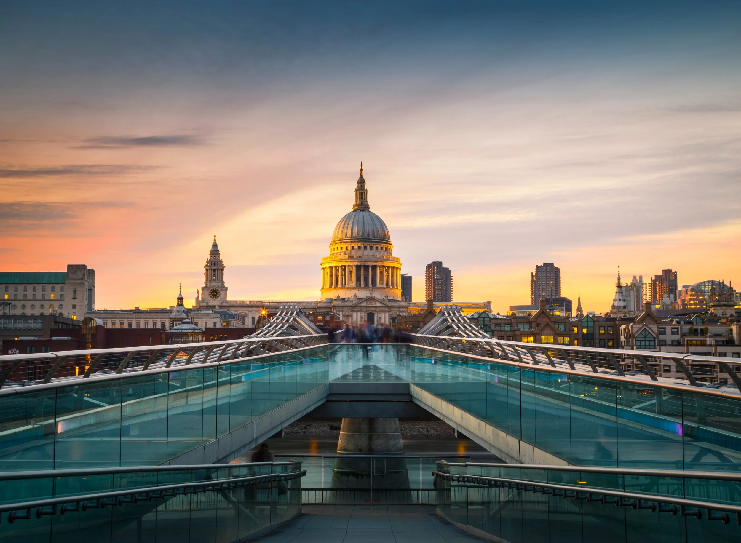 Sunset over London skyline featuring St. Paul's Cathedral with a glass rooftop terrace in the foreground.