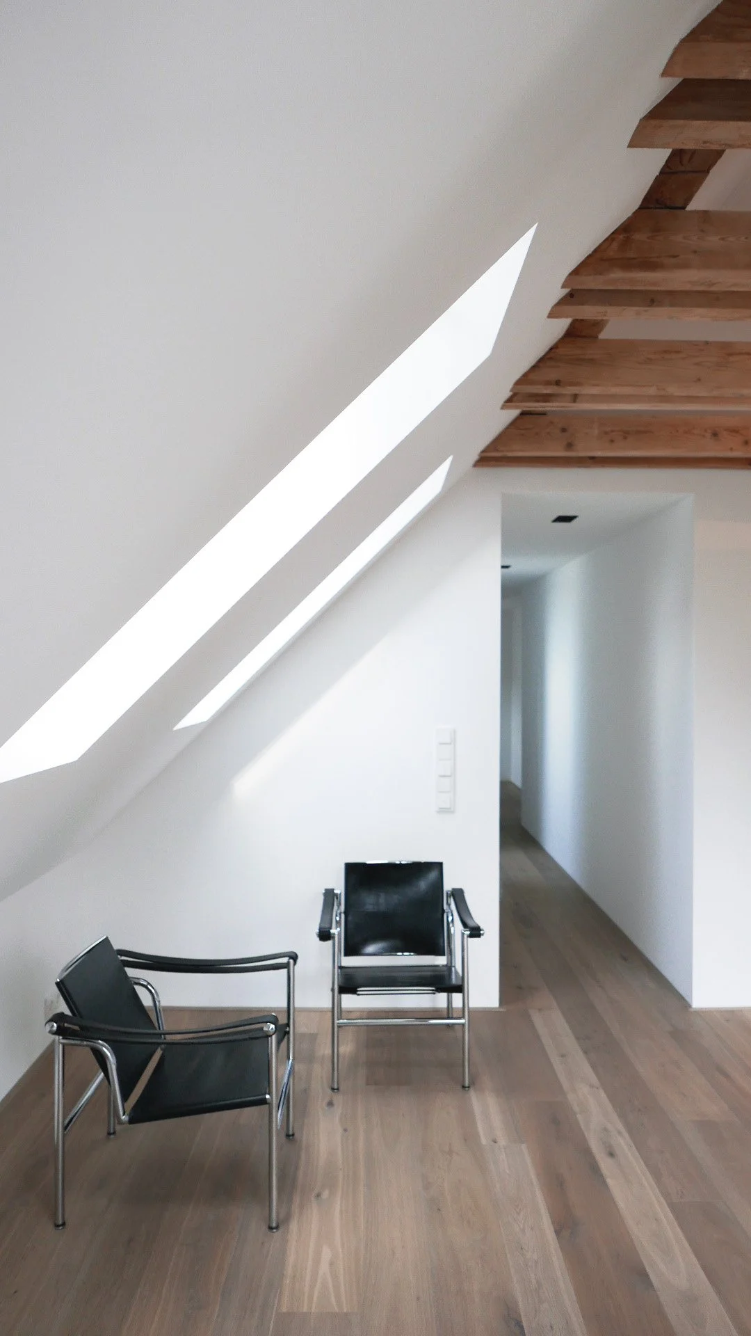 Die minimalistischen Dachfenster bieten einen schönen Kontrast und beleuchten die Altholzkonstruktion des Dachstuhls.
