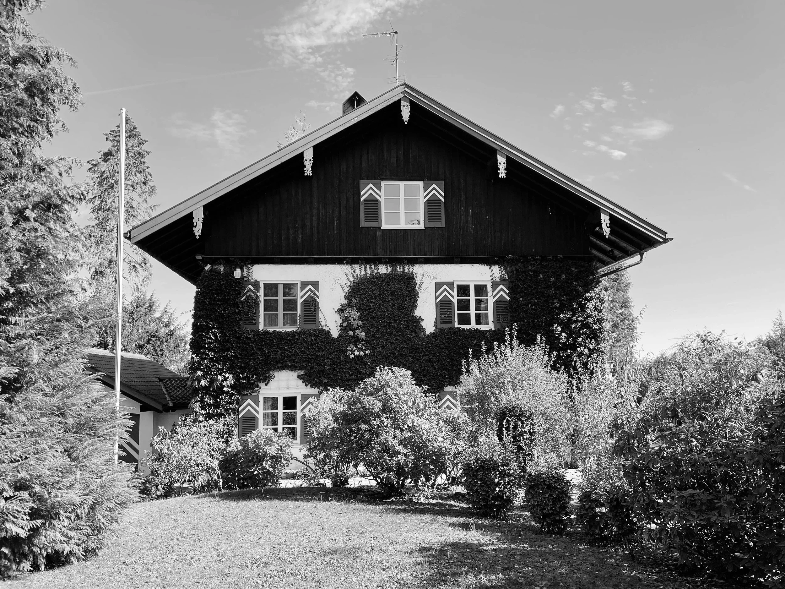 Bestandsfassade eines Einfamilienhauses mit traditionellem Holzsatteldach vor der Sanierung in Prien am Chiemsee, Deutschland