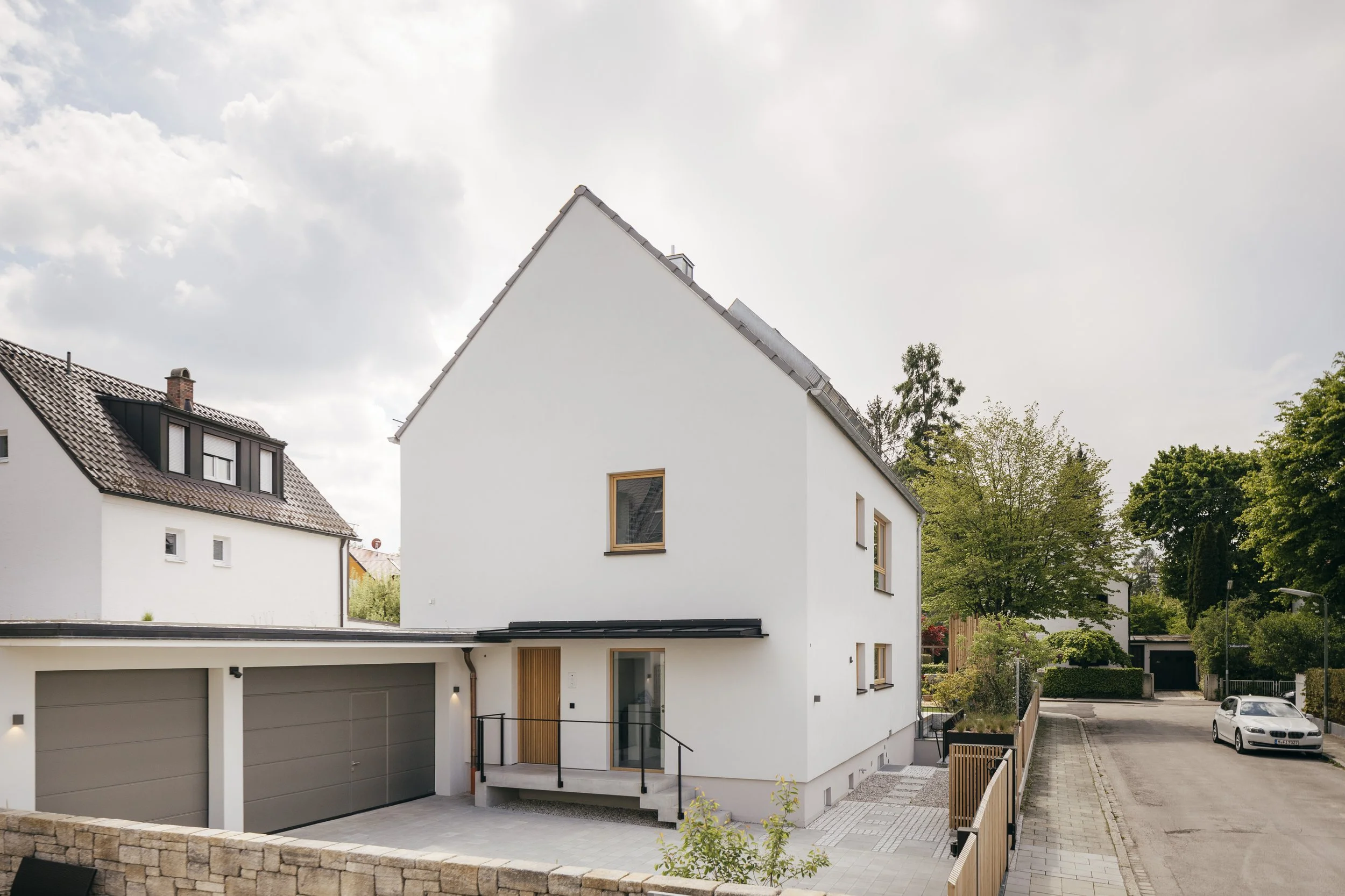 Eine überdachte Treppe führt zum Eingangsbereich des Hauses. Daneben bieten zwei Garagen viel Platz.