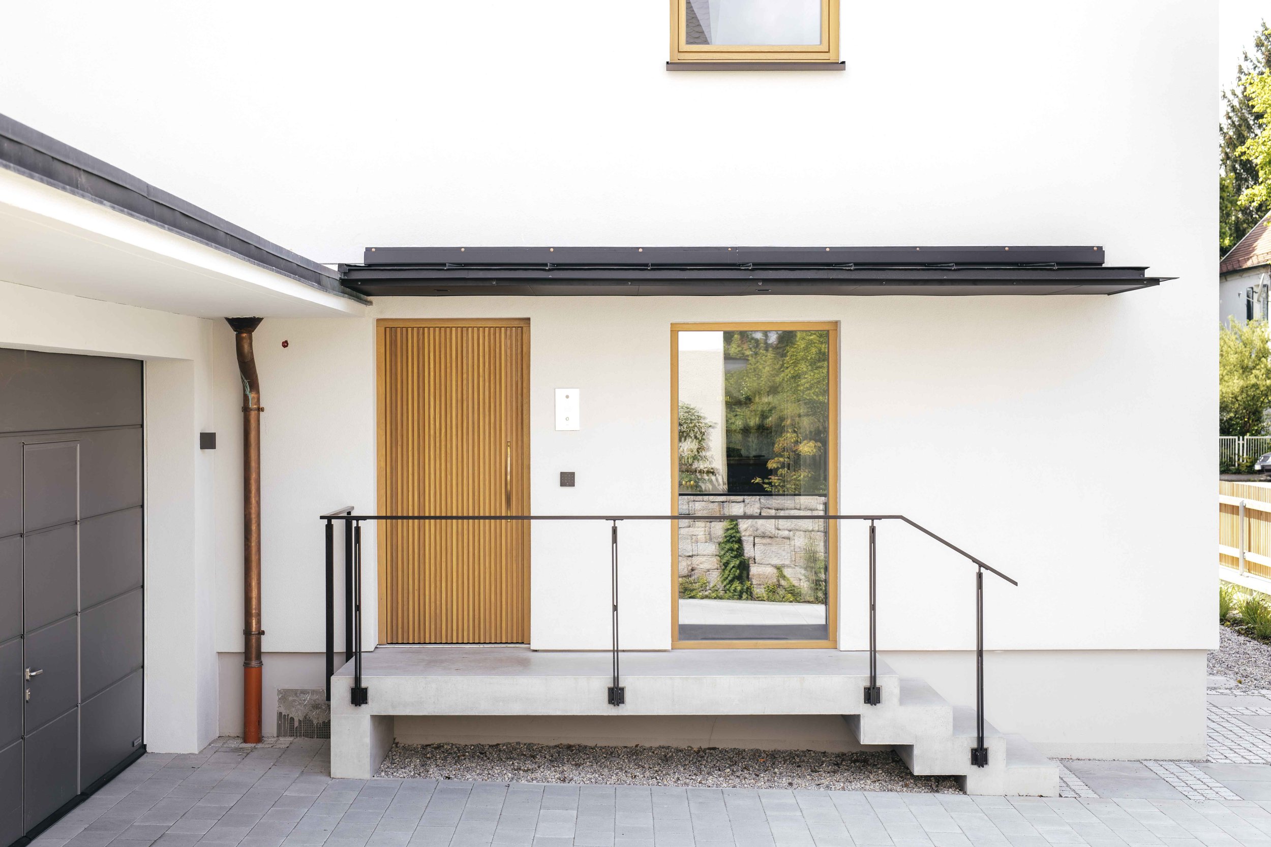 Die Eingangstür aus Eiche und vertikalen modernen aufgesetzten Leisten führen in den Eingangsbereich des Hauses