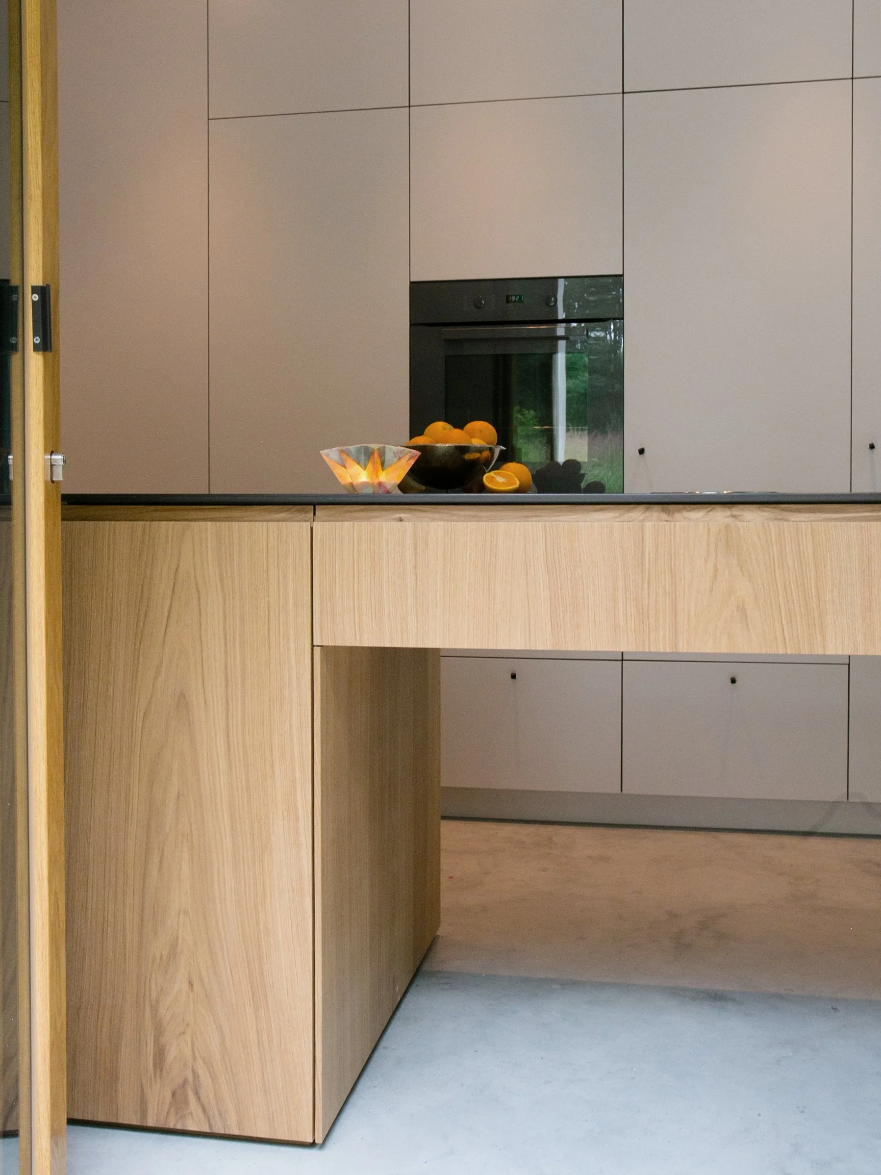 Der moderne Küchenblock aus funierter Eiche und schmalen Griffleisten unterstreicht den minimalistischen Charakter