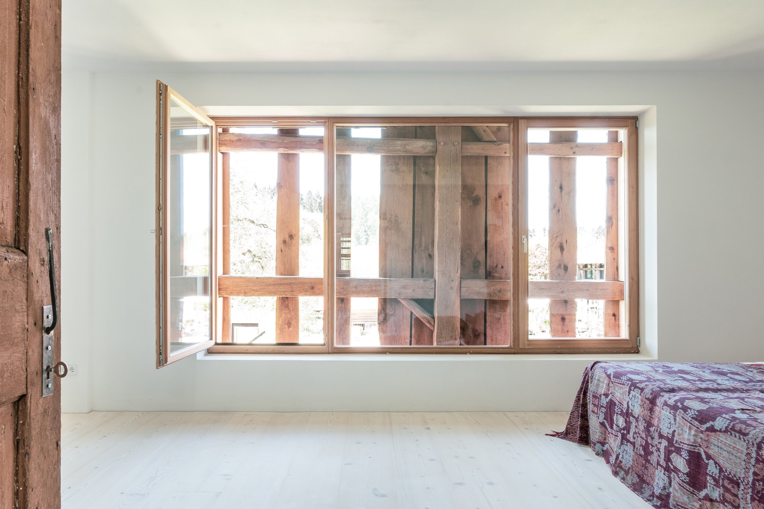 Durch das Fenster im Schlafzimmer des Bauernhauses sieht man das historische Fundwerk