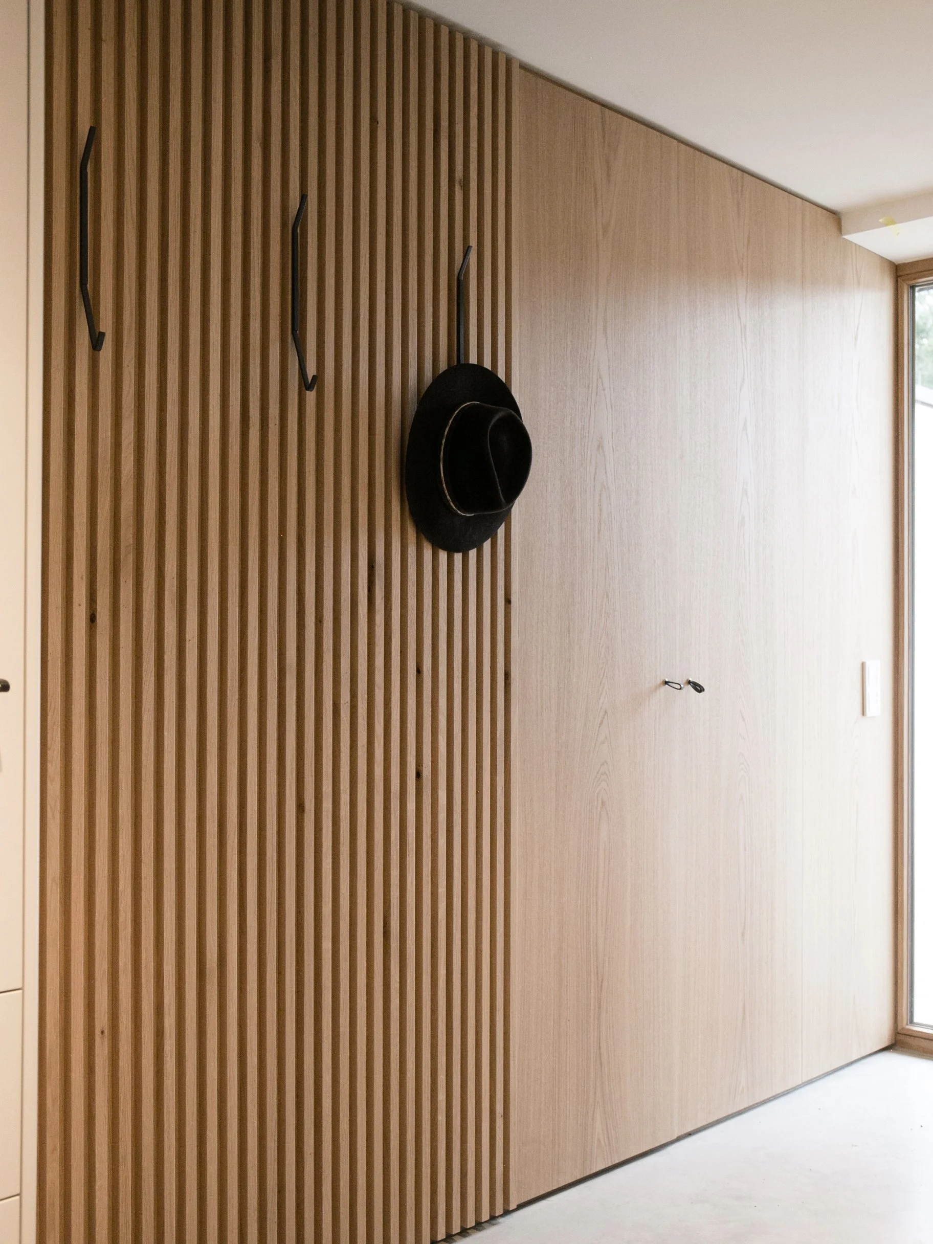 Das minimalistische Design der Garderobe im Eingang bietet viel Stauraum ohne aufzufallen.