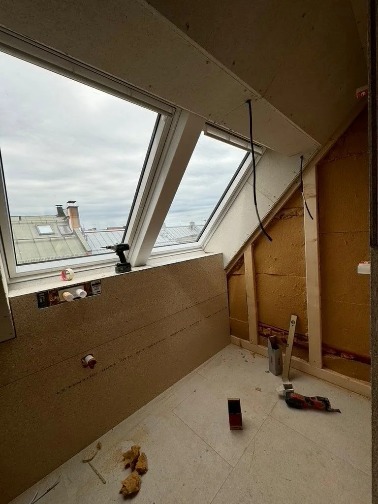 Dachgeschoss-Baustelle einer Maisonette-Wohnung in München mit verbauten Dachflächenfenstern und Wandverkleidung aus Holzwerkstoffplatten.