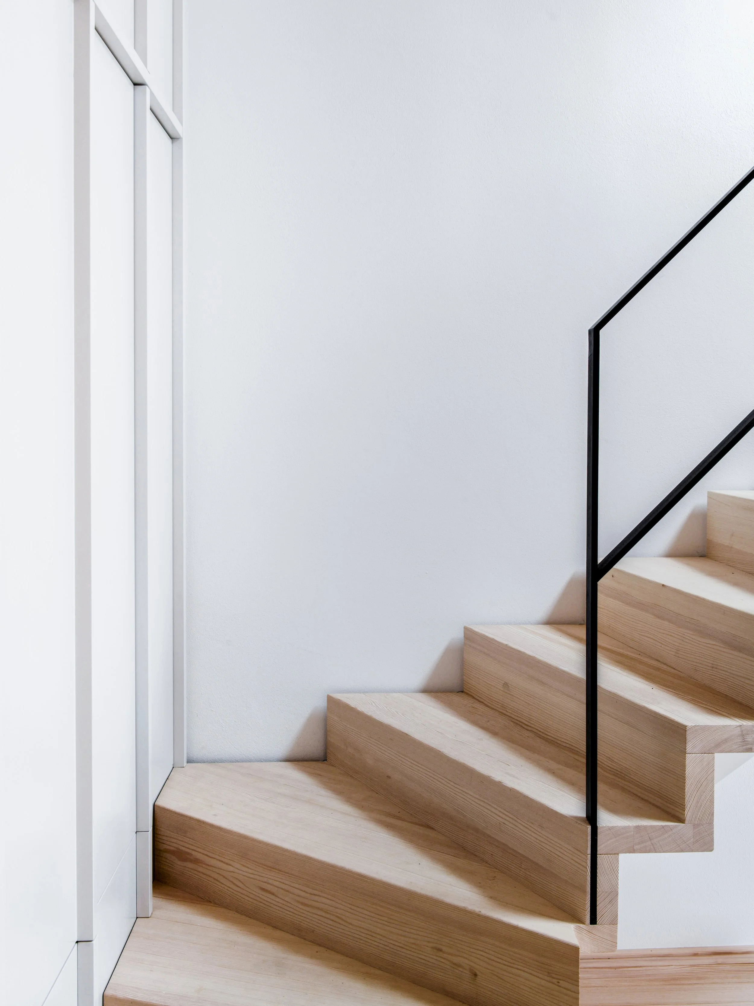 Die moderne Treppe aus Massiven Holzstufen und eingelegtem Stahlgeländer befindet sich in einem Neubau im Chiemgau