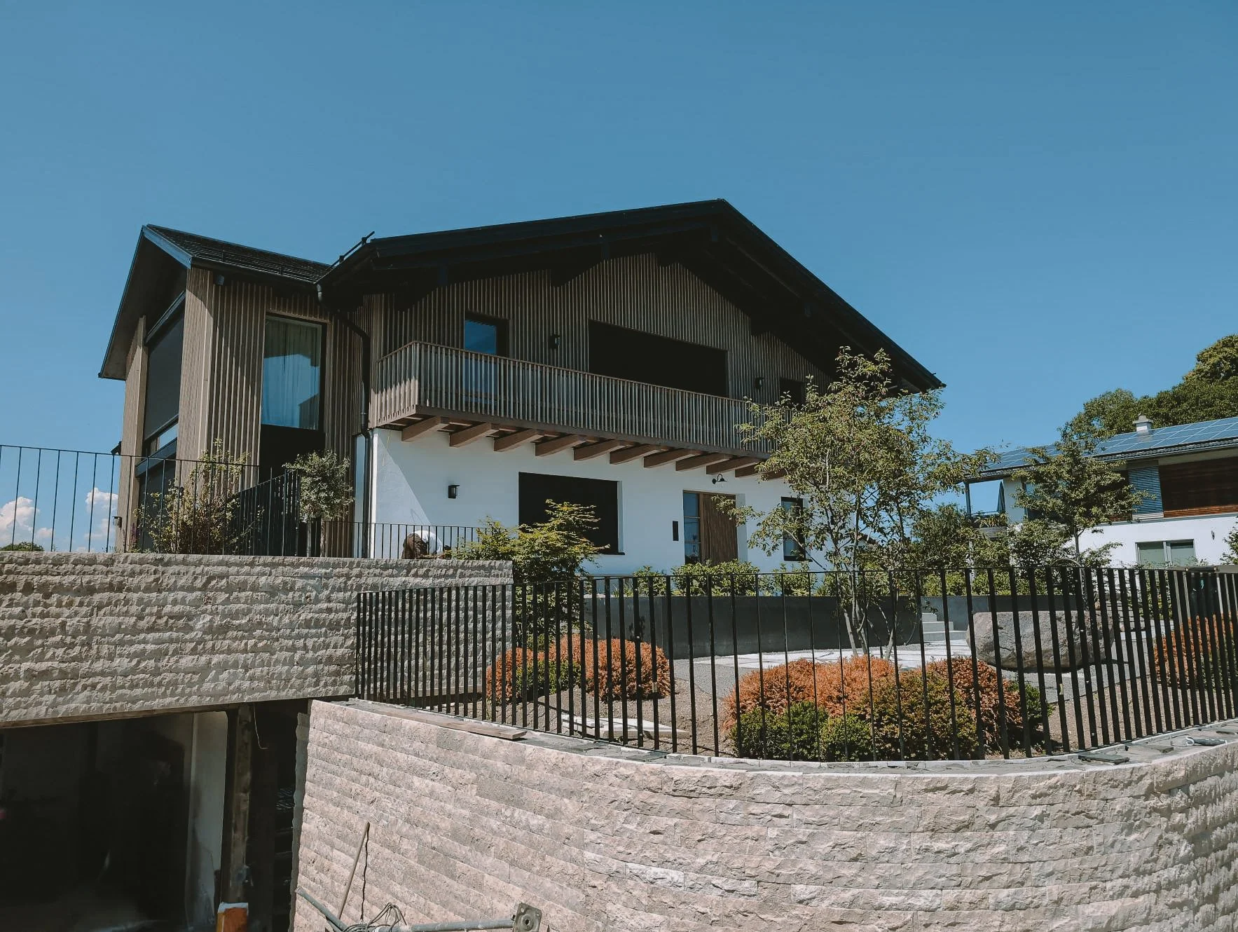 Saniertes Einfamilienhaus in Prien am Chiemsee mit Holzverschalung, Putzfassade und Natursteinterrasse