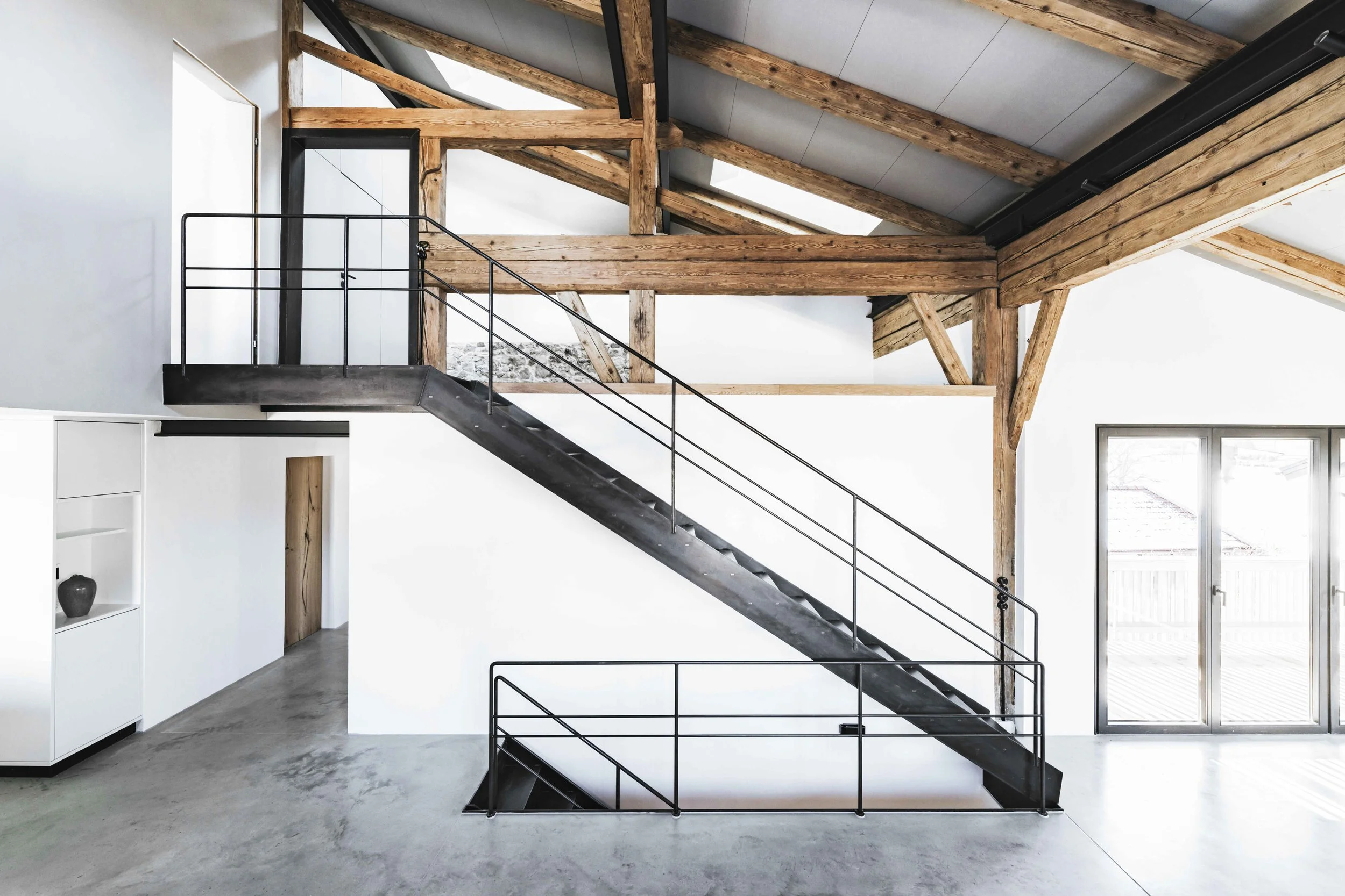 Eine elegante Stahltreppe führt zum Schlafzimmer der Tenne hinauf