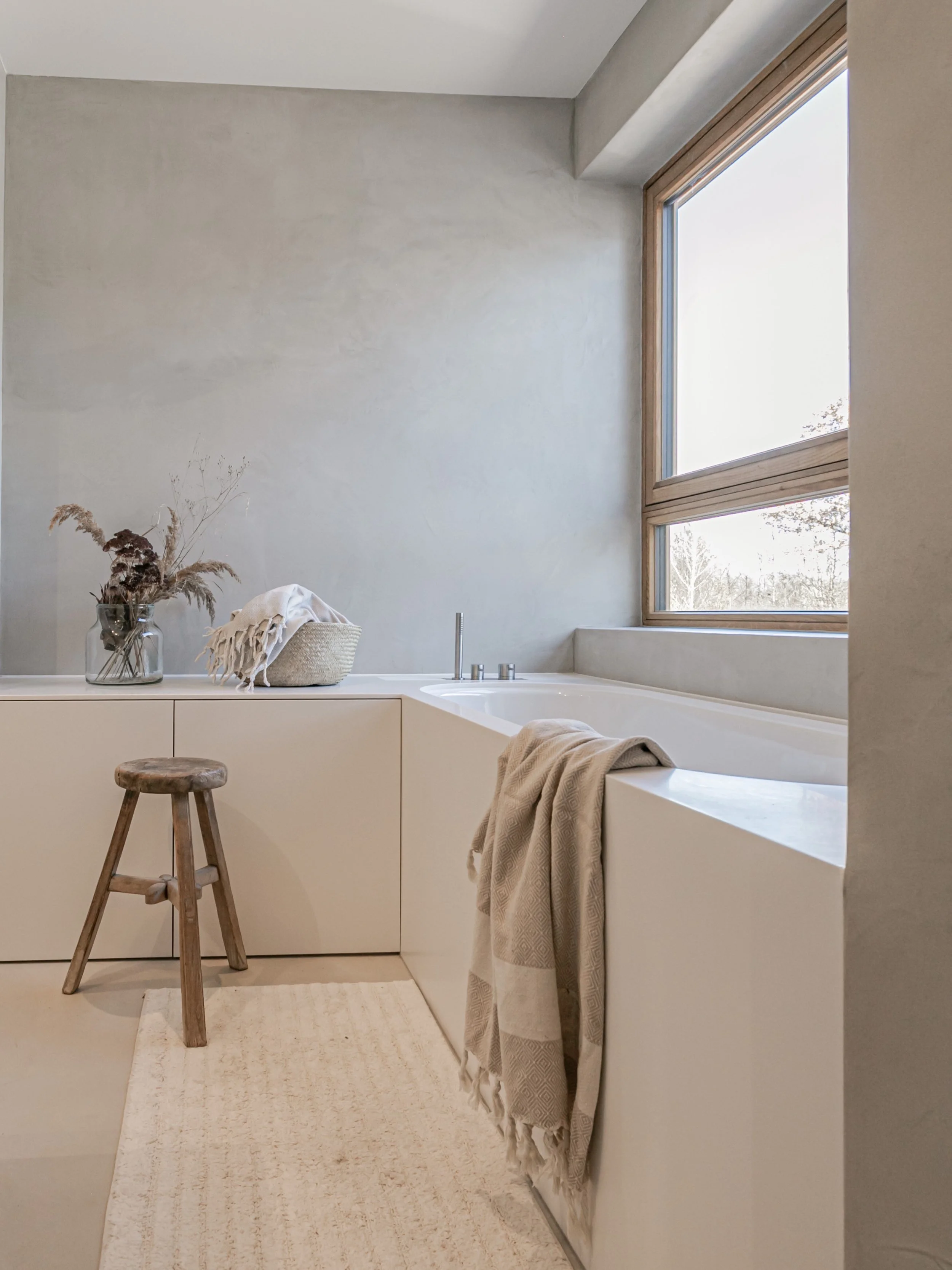 Das minimalistisch Badezimmer wurde mit Mirkozement gespachtelt und mit einer Corian Badewanne ausgestattet