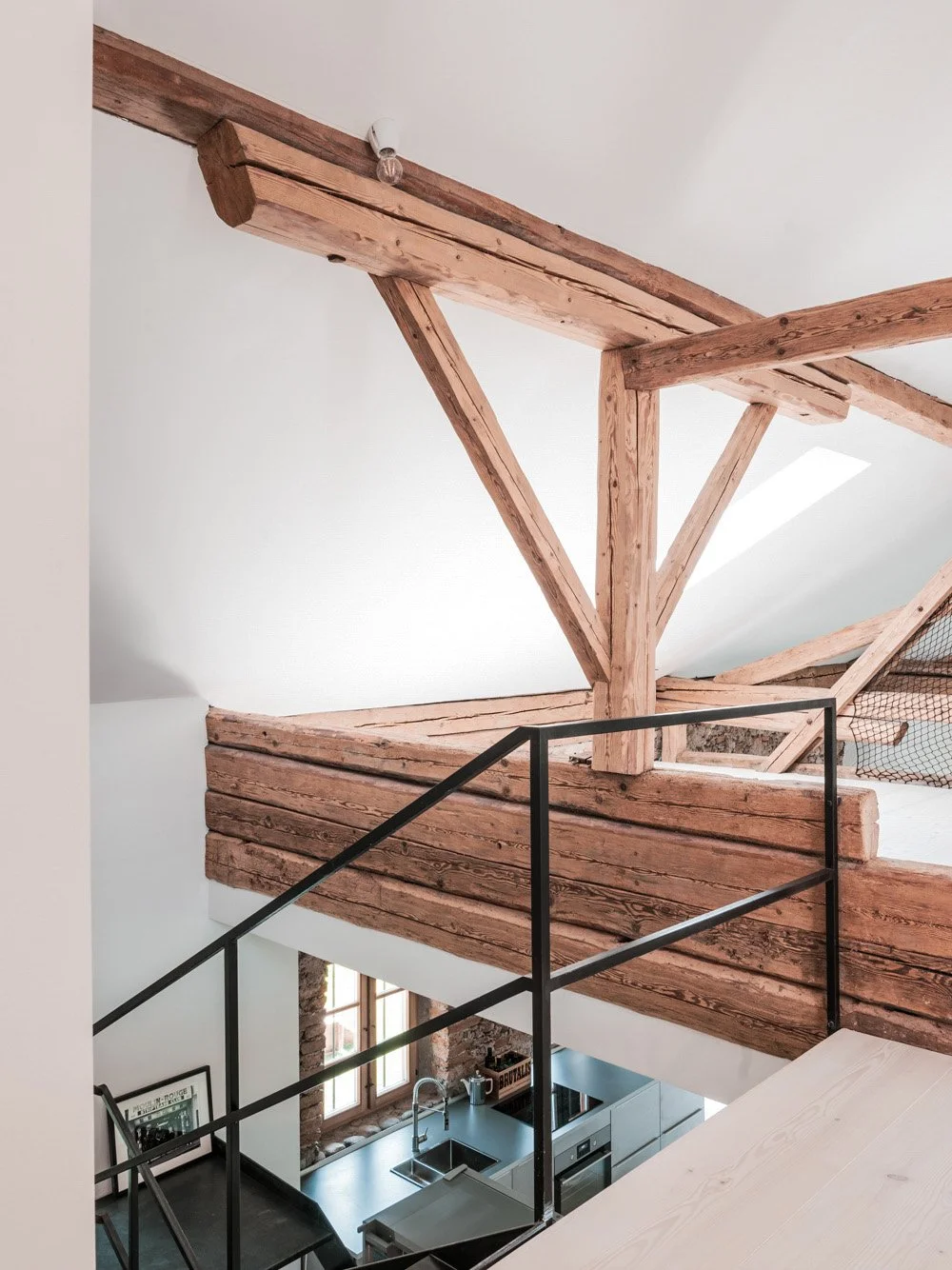 Zum Obergeschoss führt eine schlichte Stahltreppe mit Geländer. Altholzbalken geben dem Haus seinen ursprünglichen Charakter