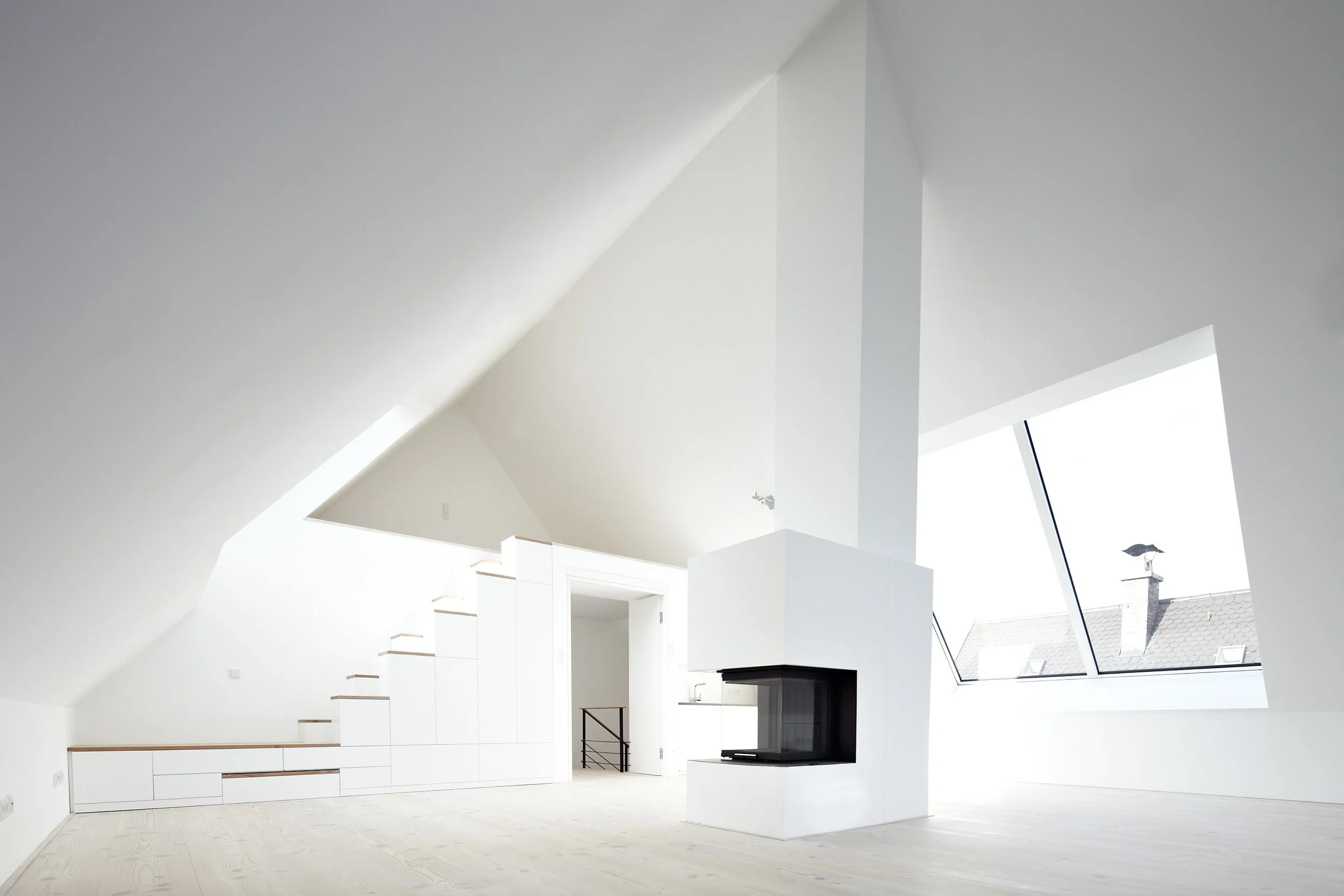 Das minimalistische Design findet sich auch im Entwurf der Treppe und des Kamins wieder in diesem Dachgeschoss in München.