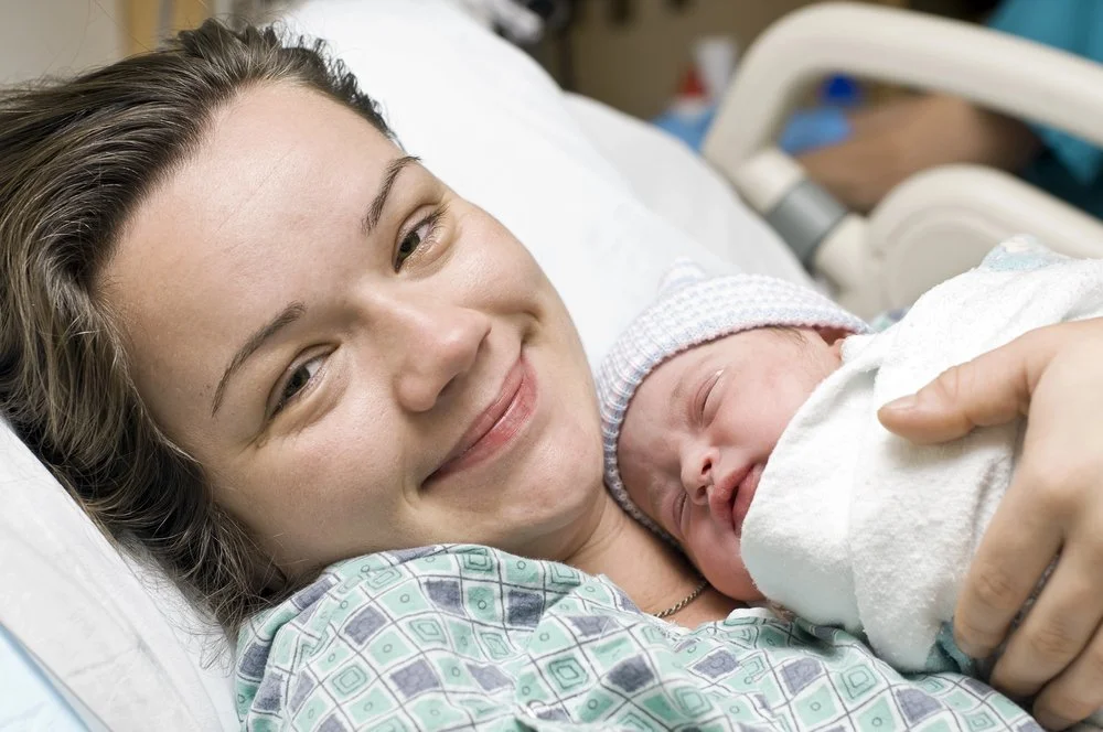 woman in a hospital gown holding a newborn baby