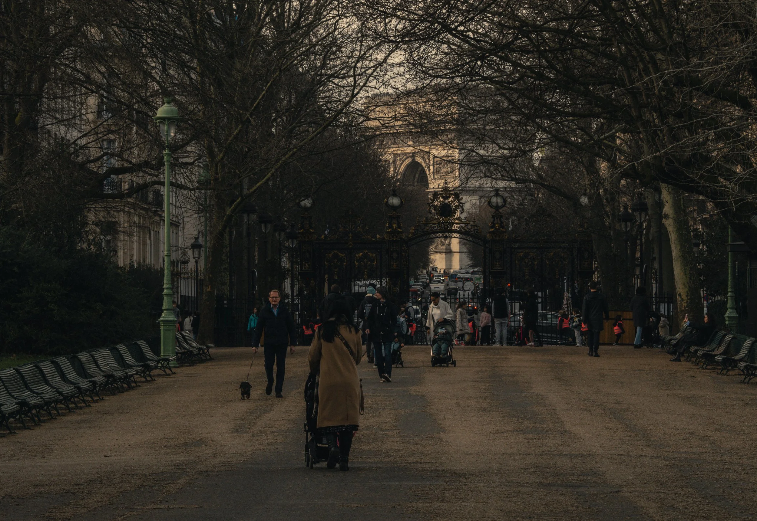 Promenade dans l'allée du Parc Monceau avec vue sur l'Arc de Triomphe à travers la grille dorée à Paris - Photographie par Théo Castillon